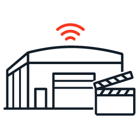 Icon showing a large industrial sound stage building with a clapperboard in the foreground and a red signal arc above the roofline, representing film studio and broadcast facility connectivity