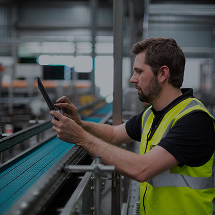 Cellular Boosting - A field engineer in a high-visibility vest working on network equipment in an industrial environment, representing on-site cellular boosting installation.png