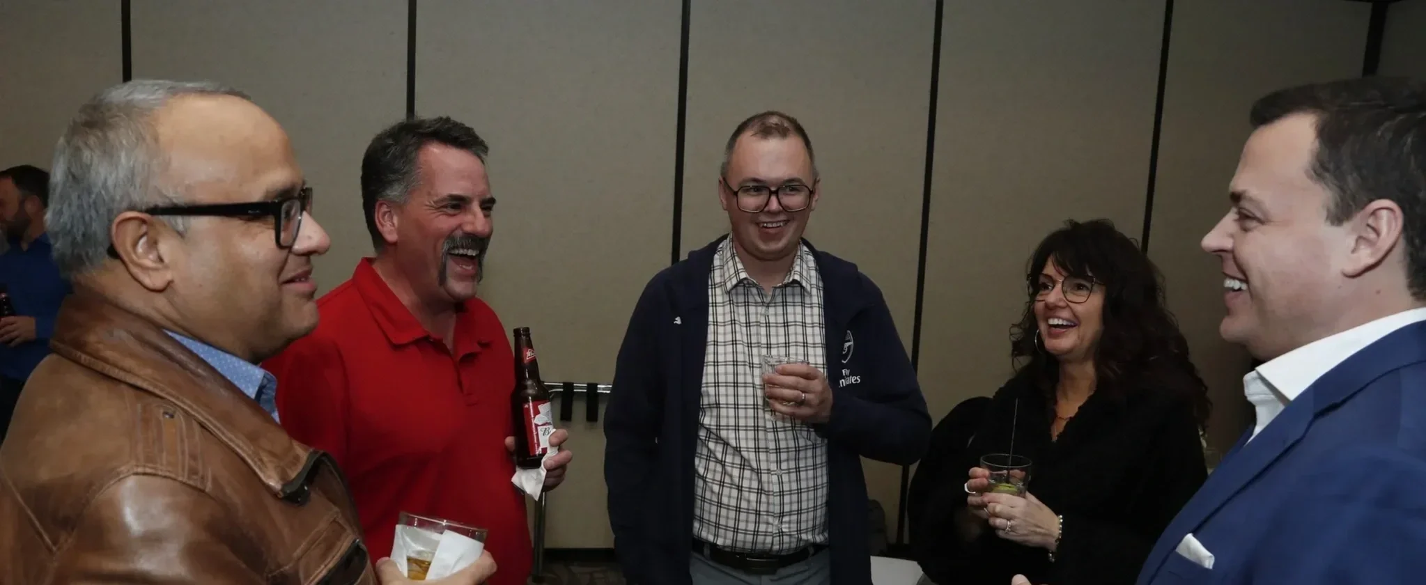 Guests laughing over drinks during Patrick Gregoire's walk-around mind reading at a corporate social