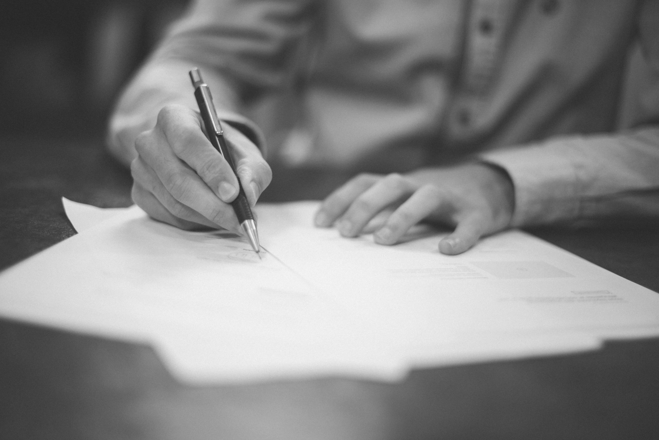 A man signing a contract or some other form of paper work.