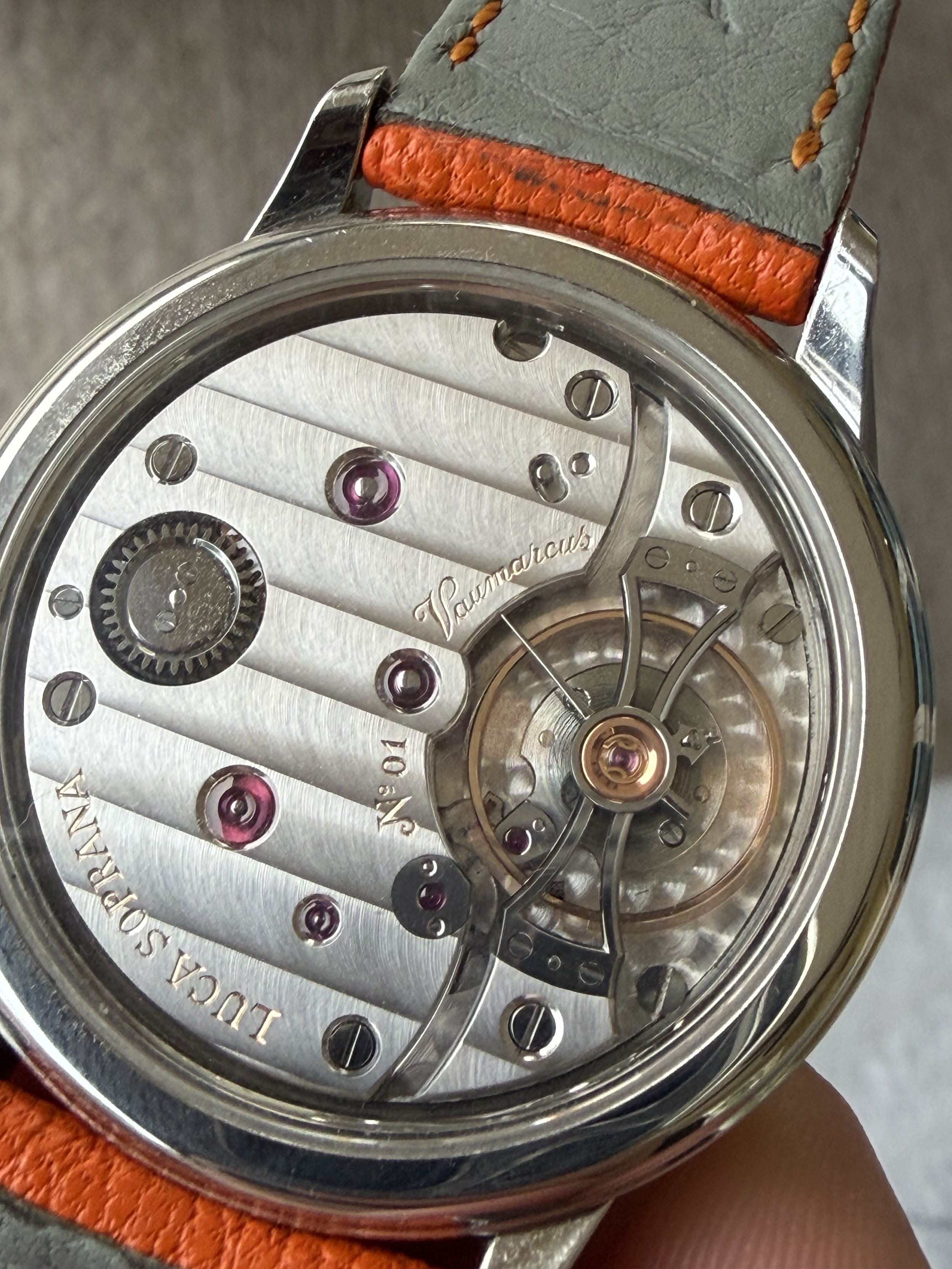 Close-up of a luxury mechanical watch with visible gears and movement, engraved details, and a leather strap.