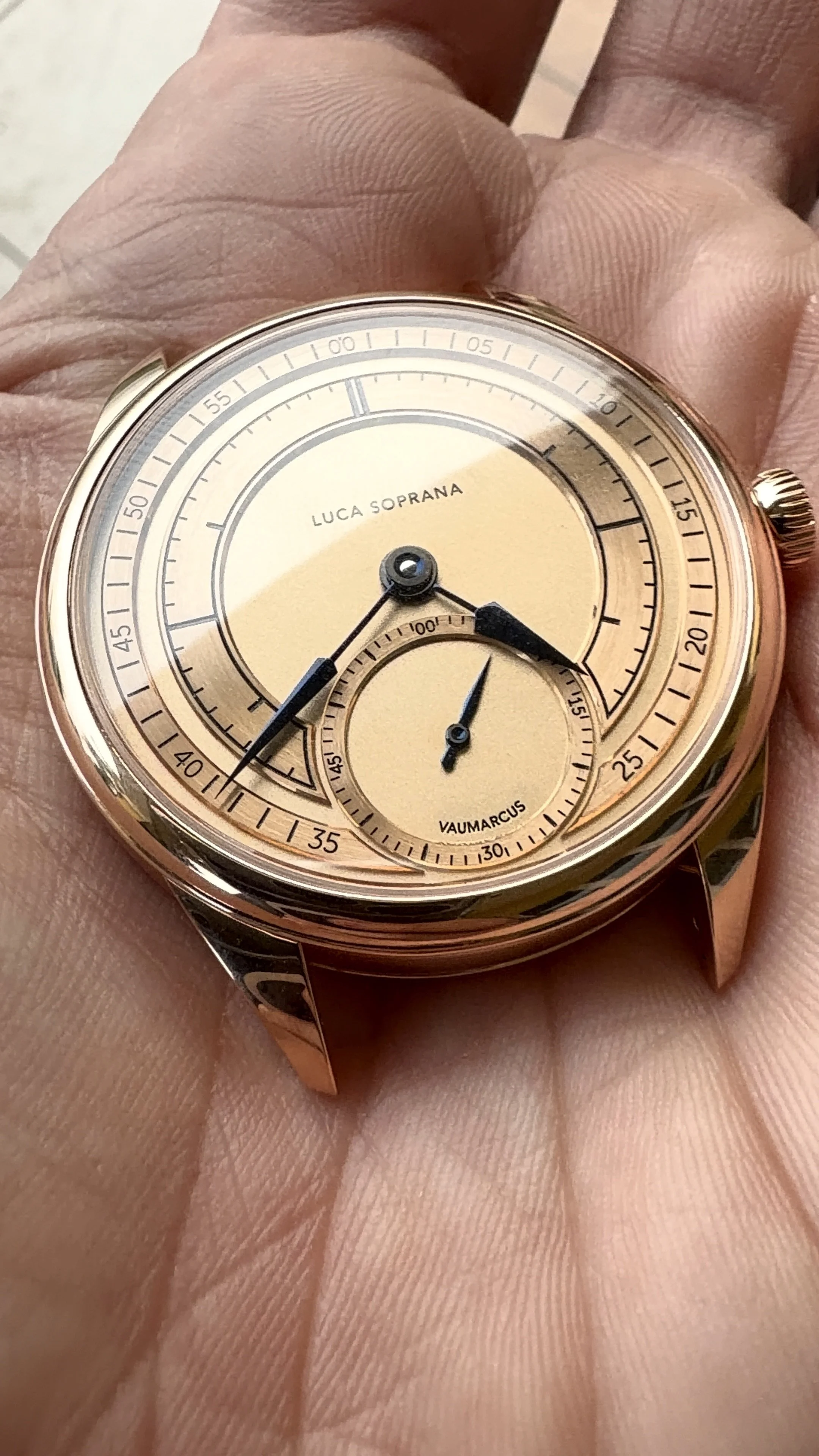 A close-up of a gold-tone Luca Soprana watch with a beige dial held in a person's hand.