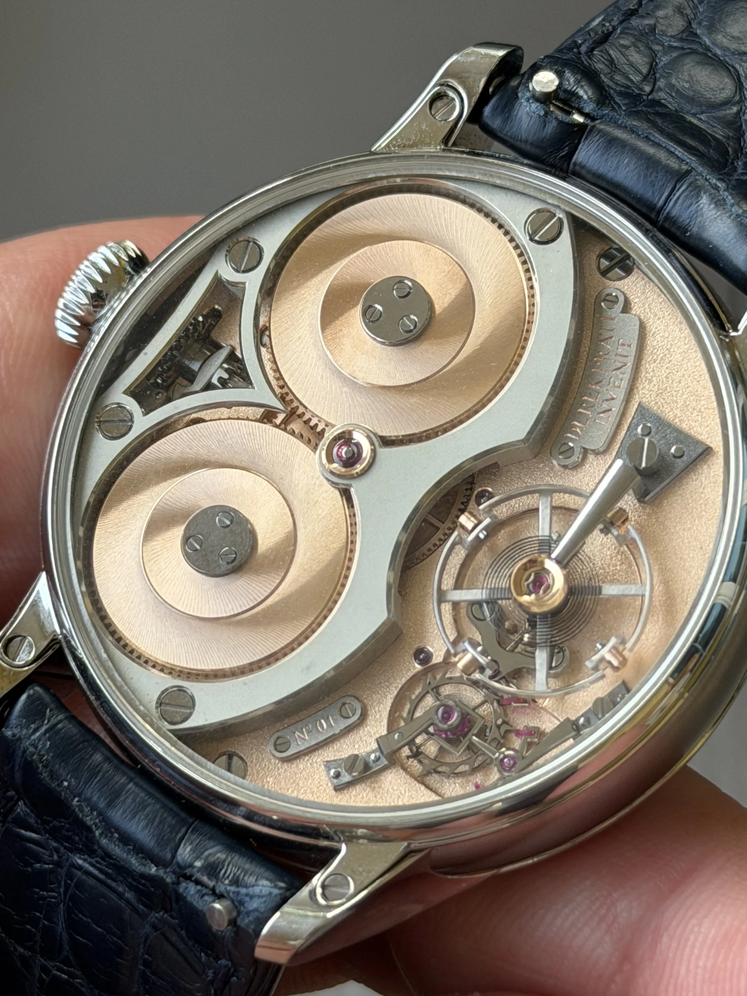 Close-up of a luxury watch with a skeleton dial, showcasing intricate inner mechanisms, gears, and jewels, with a black leather strap.derek pratt movement dp07