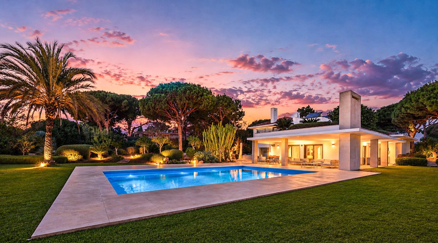 Casa moderna com piscina ao entardecer, iluminação externa, jardim bem cuidado com árvores e plantas tropicais.