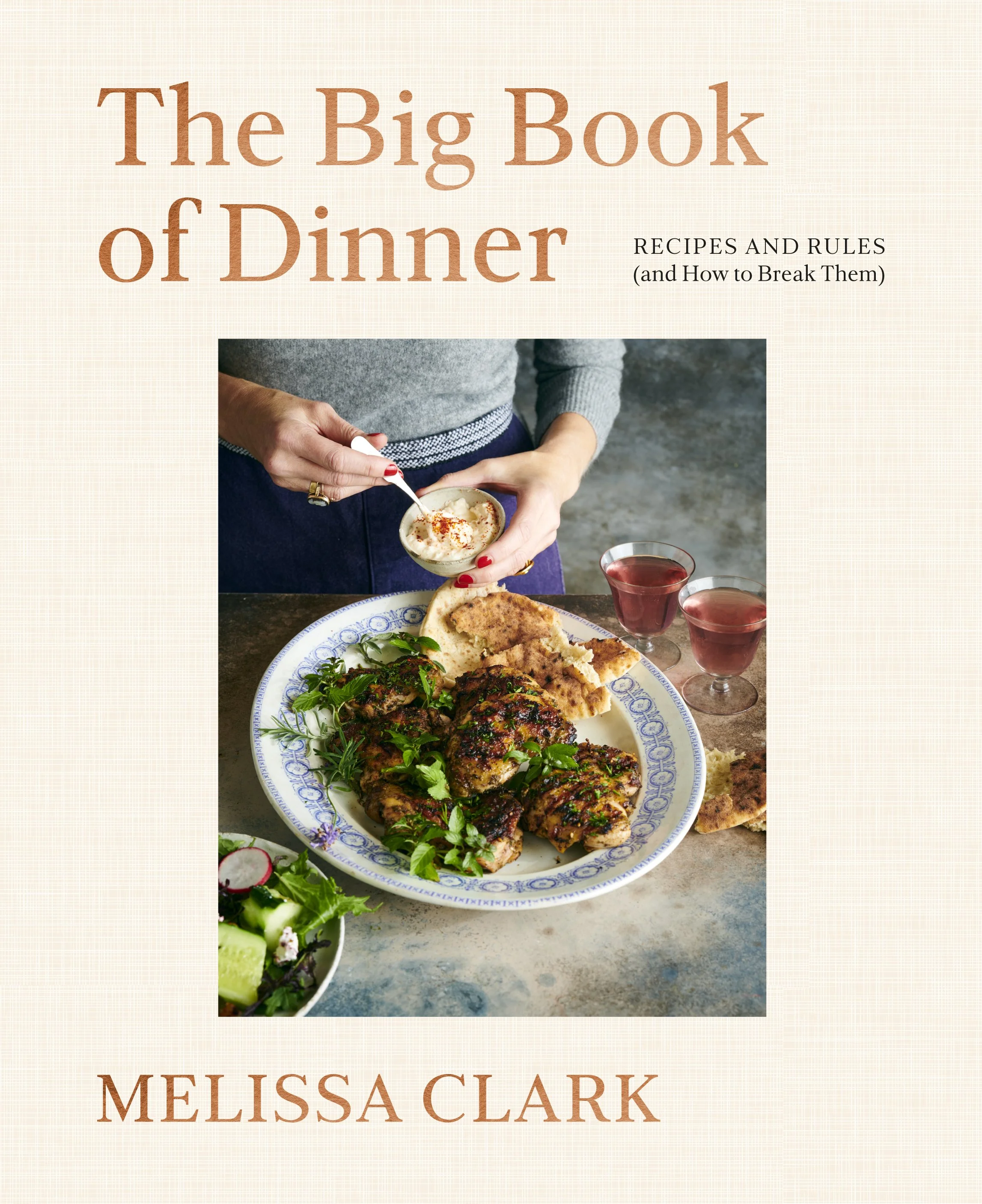 Book cover titled "The Big Book of Dinner: Recipes and Rules (and How to Break Them)" by Melissa Clark, featuring a picture of a person holding a bowl of dip and a plate of grilled meat and bread, with a salad and drinks on a table.