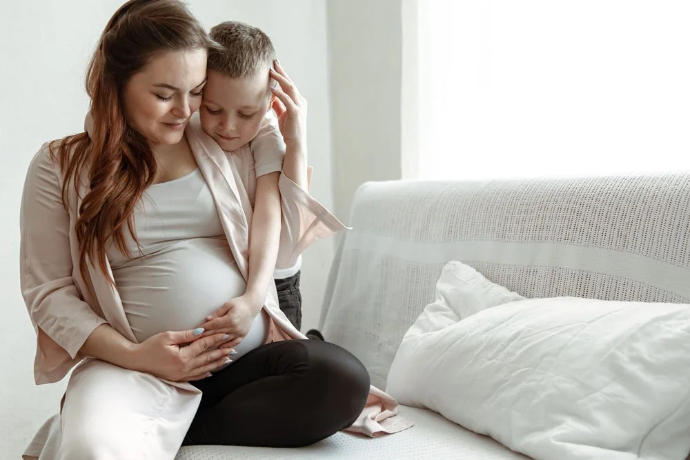 A young child hugging a pregnant parent at home