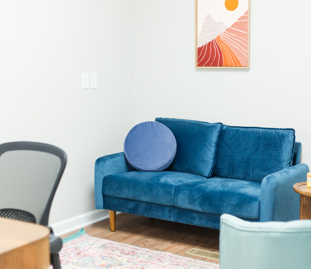 A calm Soul Story Therapy office with a blue loveseat and soft natural light