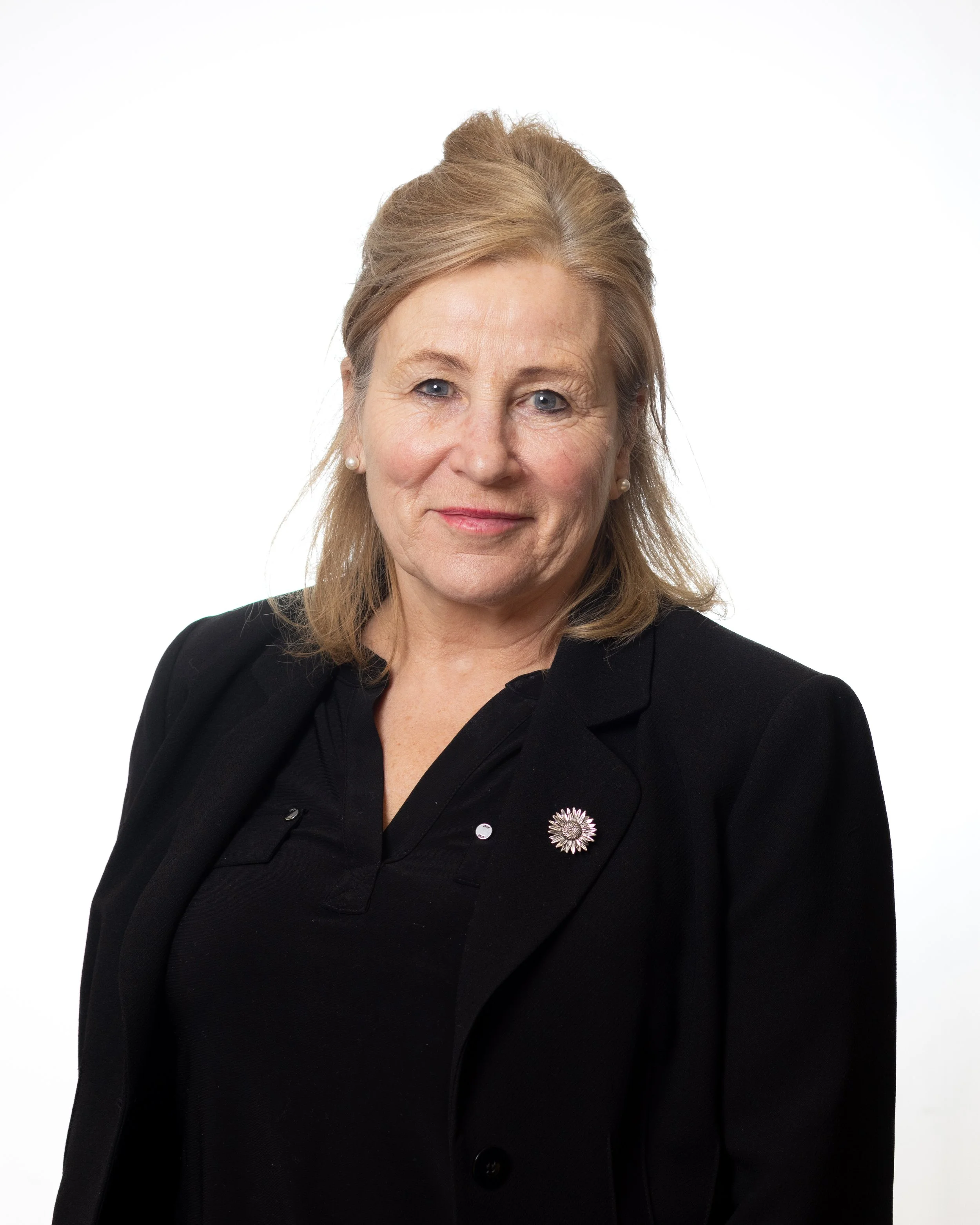 A professional looking woman in a smart black jacket. She has shoulder length hair neatly styled.