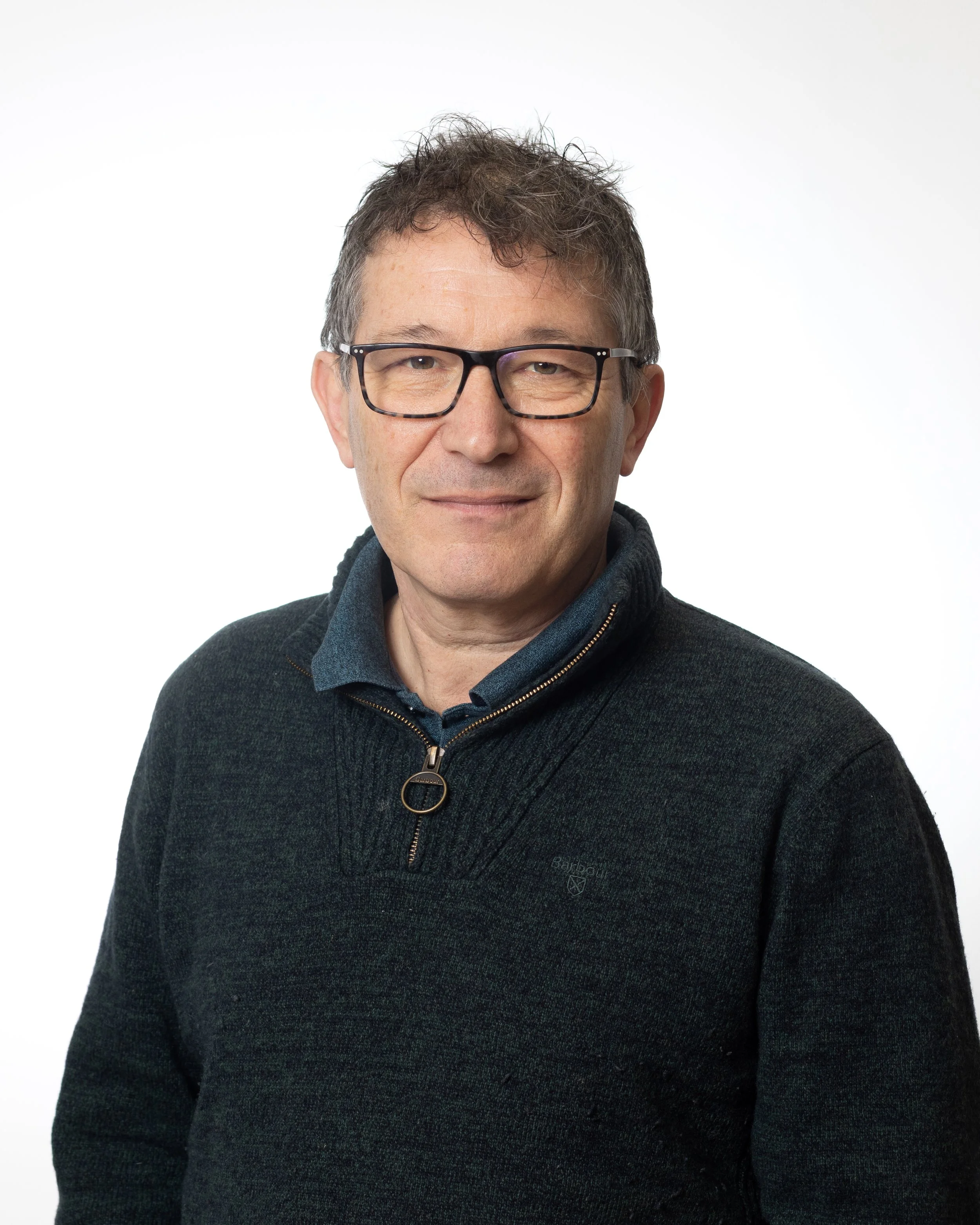 Middle aged man with dark hair, wearing a dark blue shirt