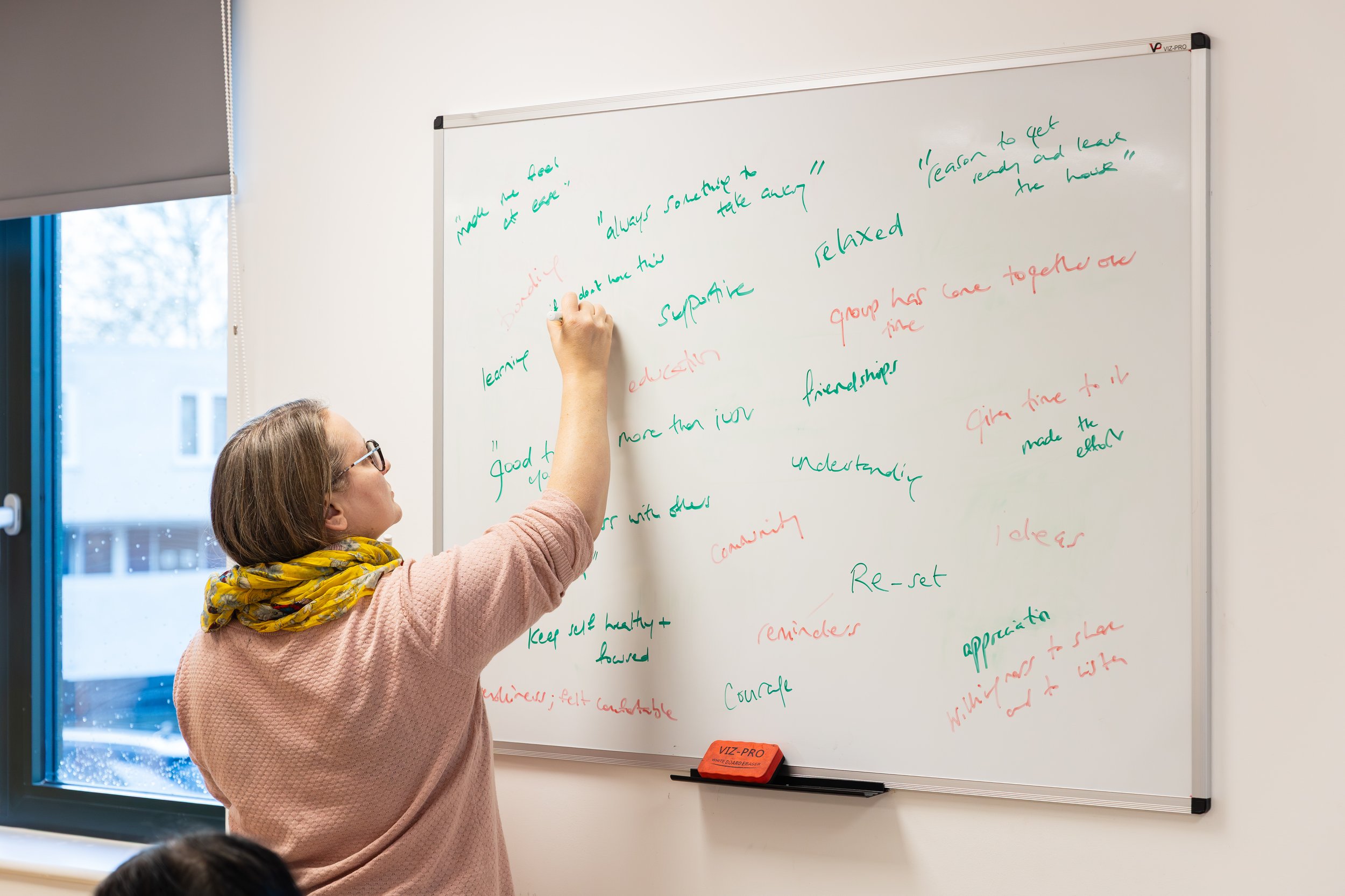 A woman writing on a whiteboard.