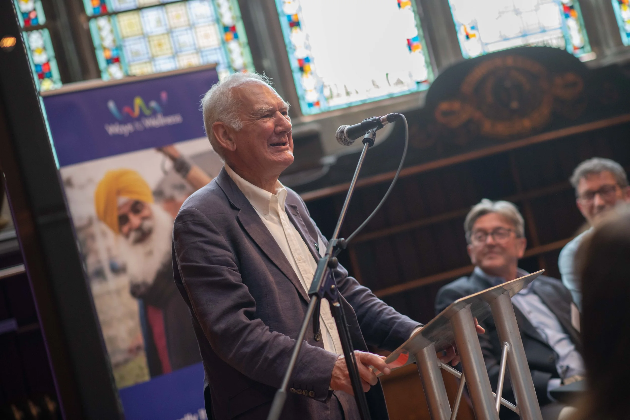 An older man standing at a lectern to speak.