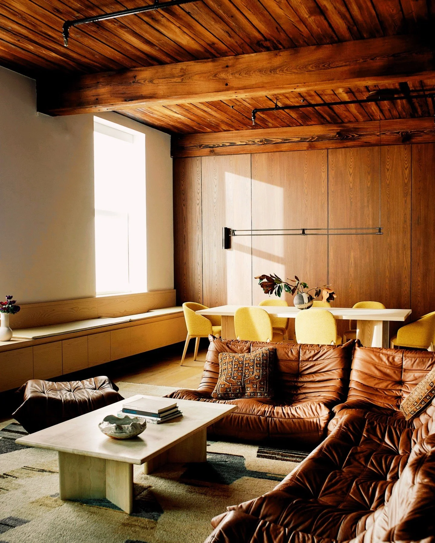 Exposed timber beams frame the living area, where Togo seating meets built-in dining. Afternoon light fills the space, warm oak and cognac leather softening the volume in this Brooklyn loft.

Photo @skylerrsmith 
Styling @pammorris

#boleearchitects 