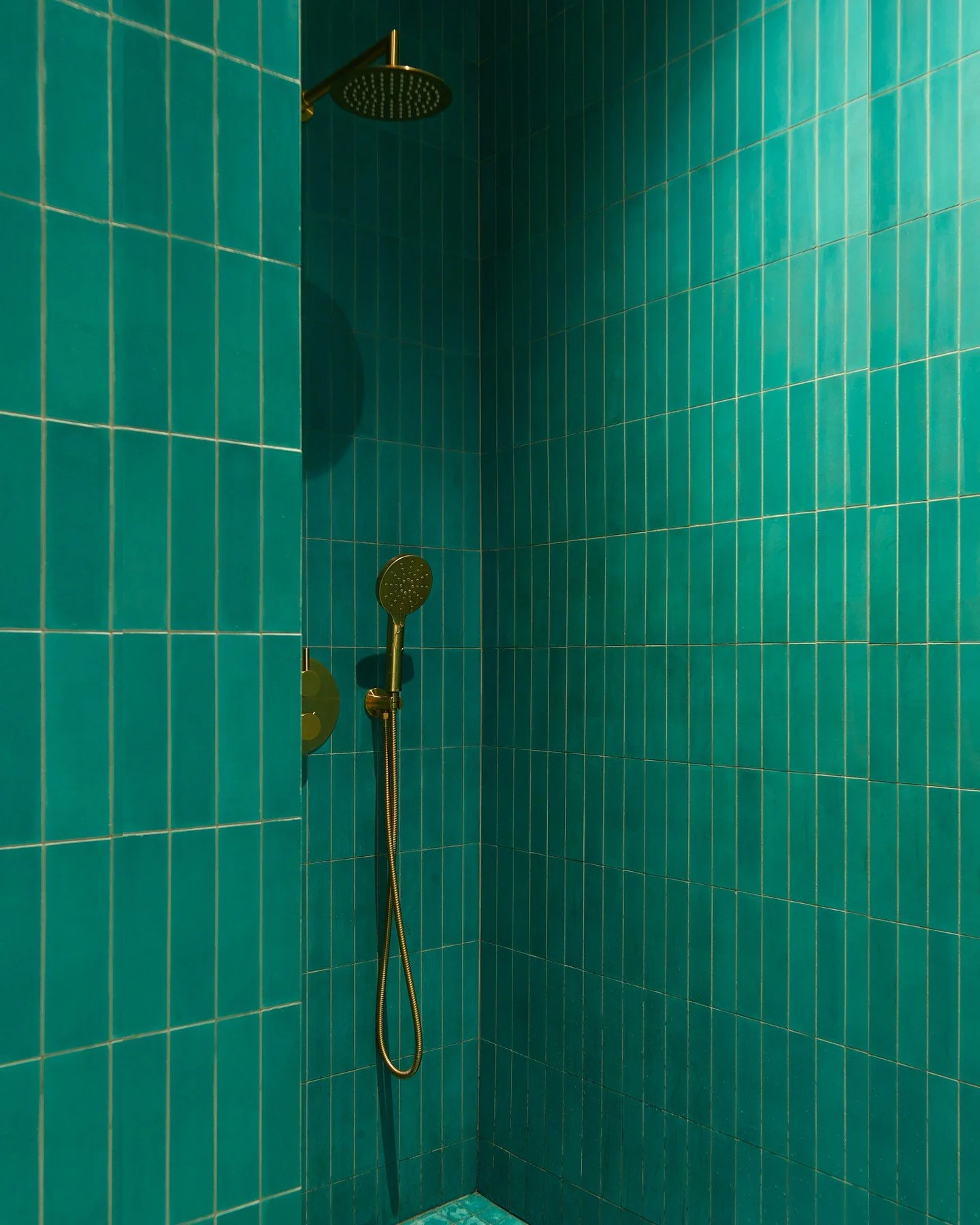 Emerald cement tile and brass fixtures transform this primary bath into a richly layered retreat, while scalloped hand painted tile in deep blue and green gives the guest bath a playful energy. They're proof that the smallest rooms can make the bigge