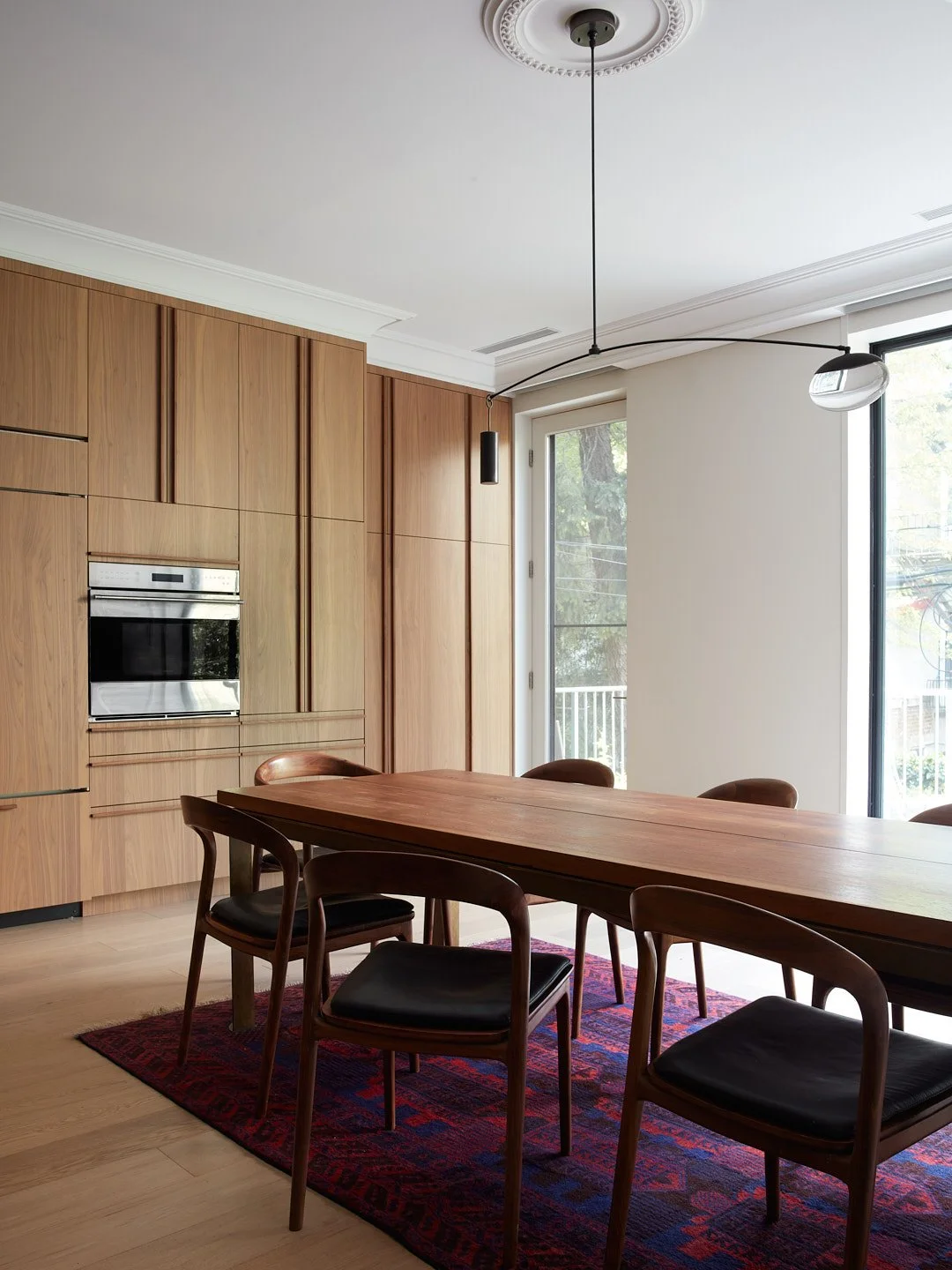 We love this big, open kitchen designed for a family that loves to cook. A custom full-height walnut pantry integrates the refrigerator, wall oven, deep pull out drawers, and an appliance garage hidden behind pocket doors. A window wall connects the 