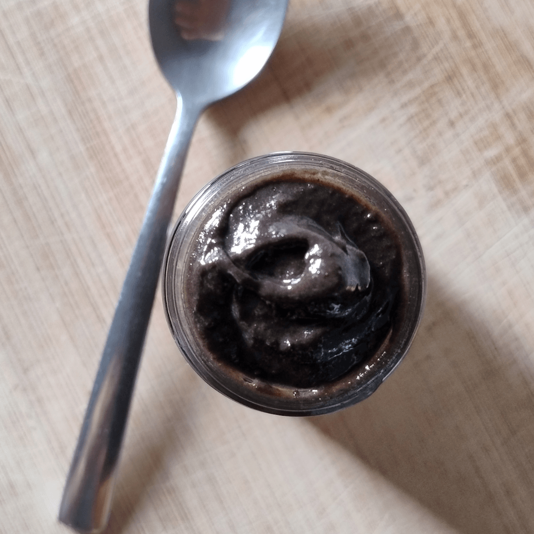 Aerial view of an opened jar of CHyawanprash with a spoon next to it.