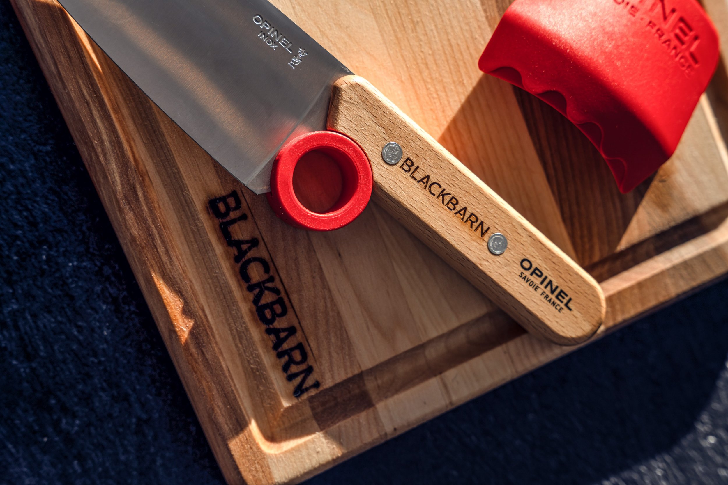 A first real knife is a big day for a young cook. Our kids set pairs the Opinel Le Petit Chef knife, engraved with our name, with a BLACKBARN cutting board of their own. The rounded tip and finger ring teach the right grip from the start, and the red