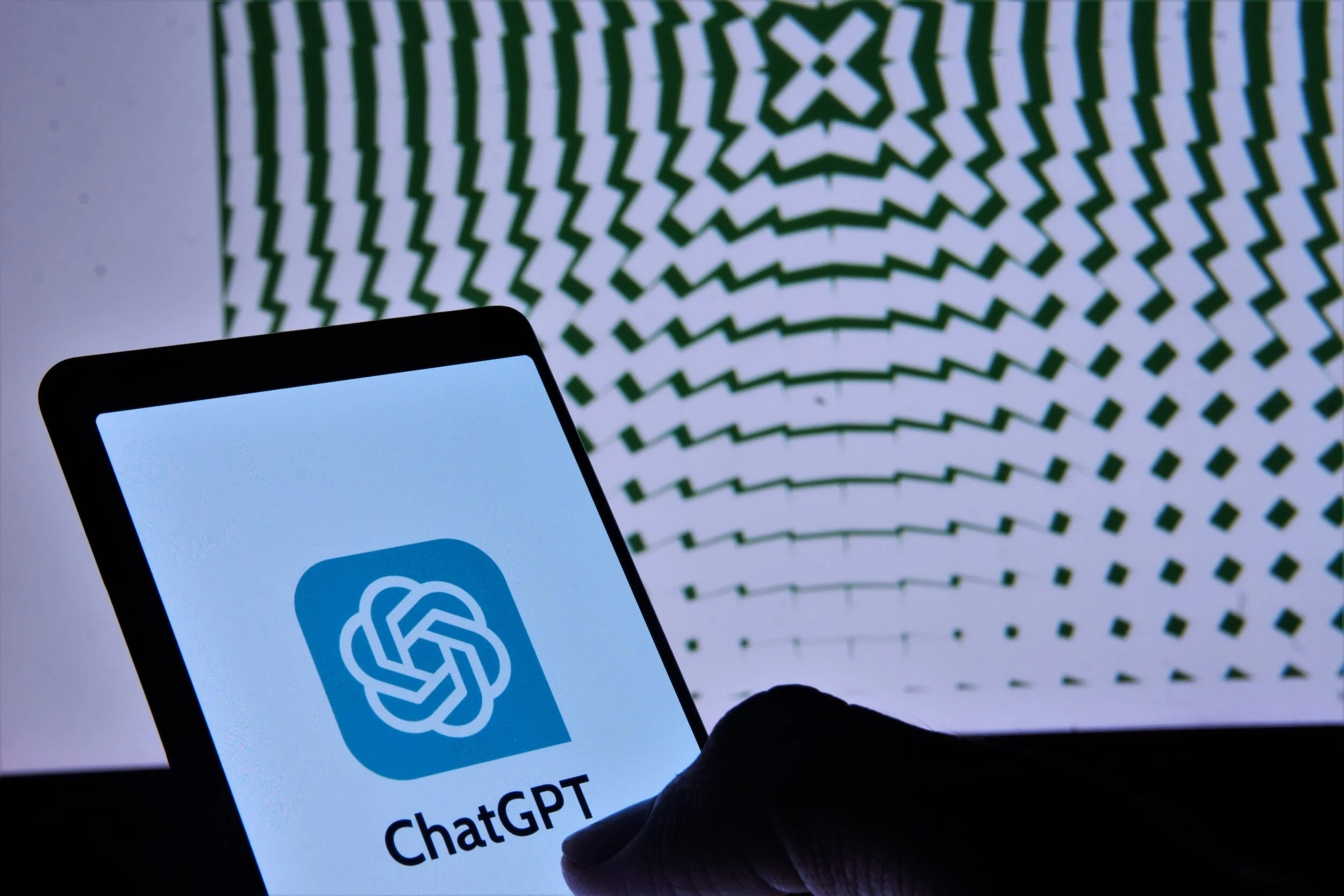 Phone with text that says ChatGPT and geometric pattern in background