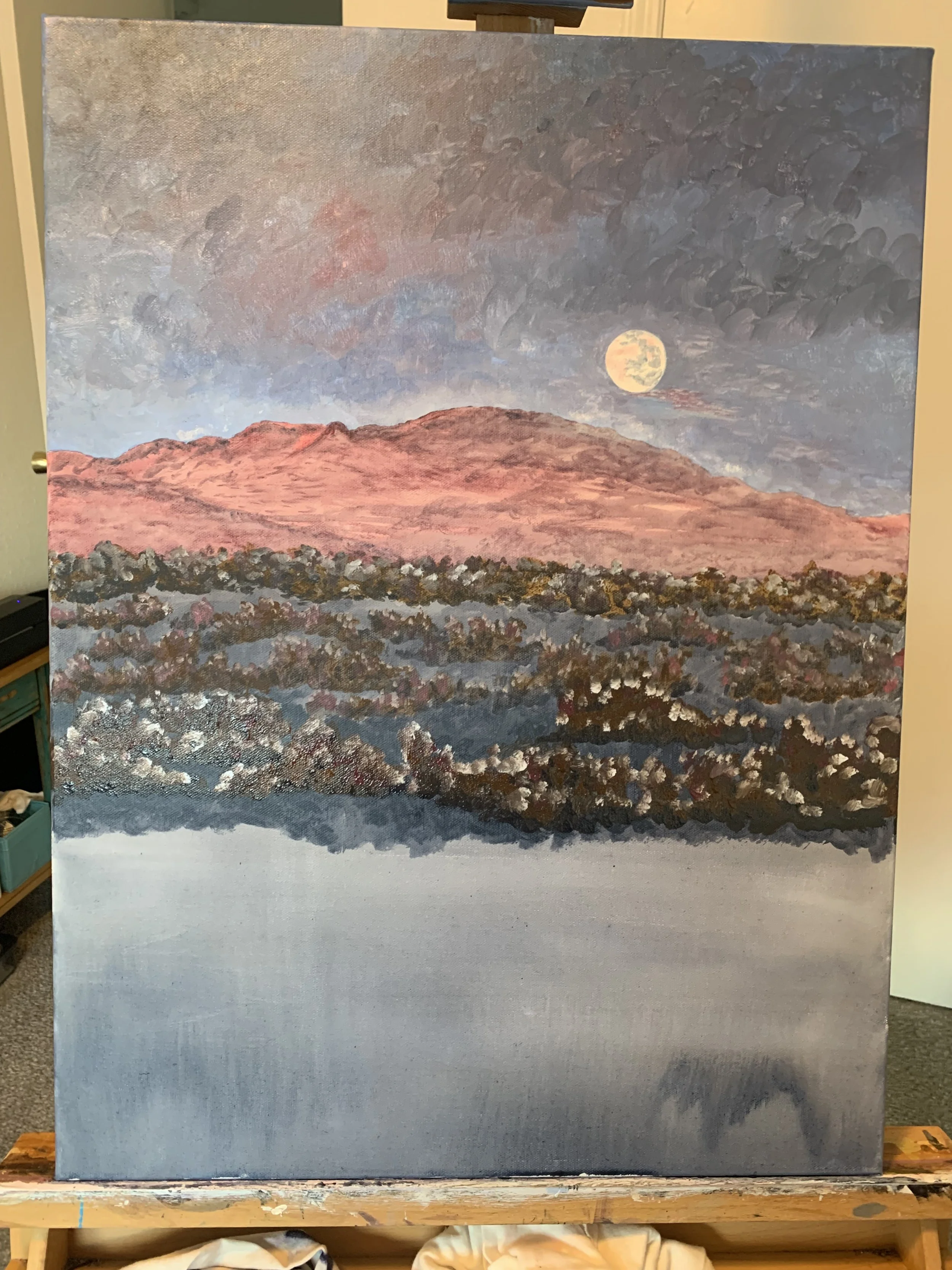 Landscape painting depicting a desert scene with hills, a full moon in a cloudy sky, and a reflective body of water in the foreground.