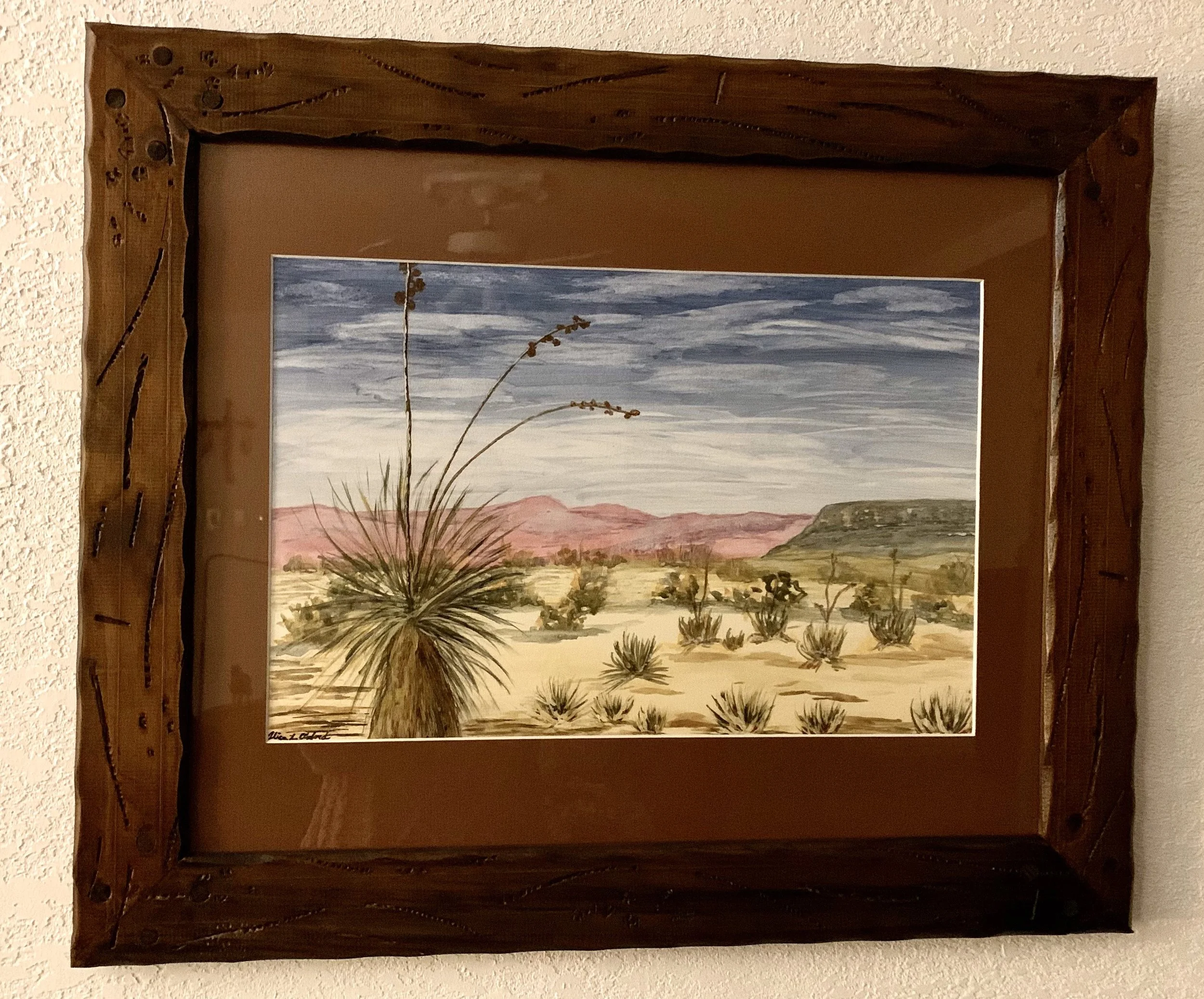Alice Oxford's framed desert landscape painting with a yucca plant, distant mountains, and cloudy sky.