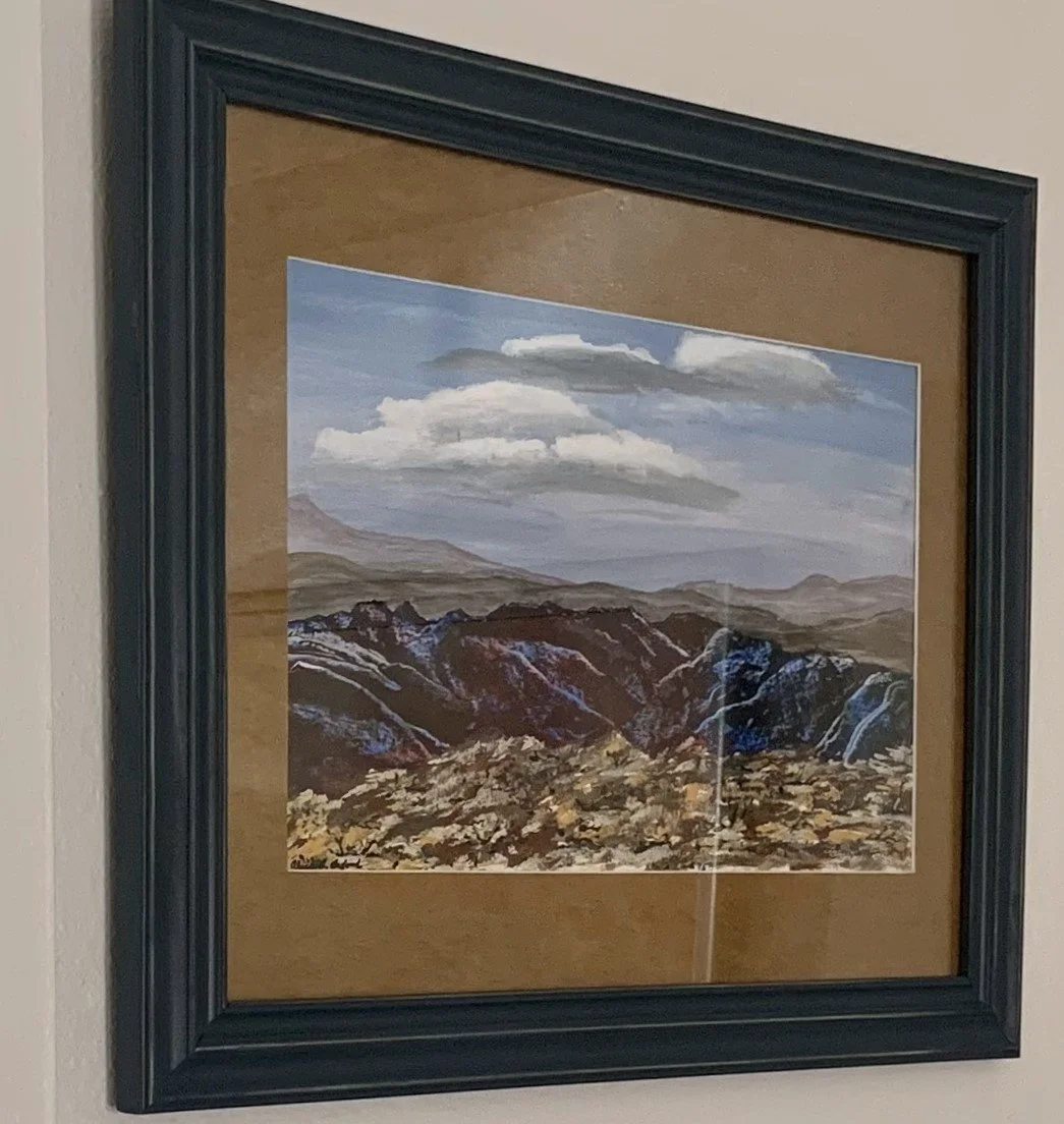 Alice Oxford's original framed landscape painting depicting a mountainous scene with clouds in the sky.