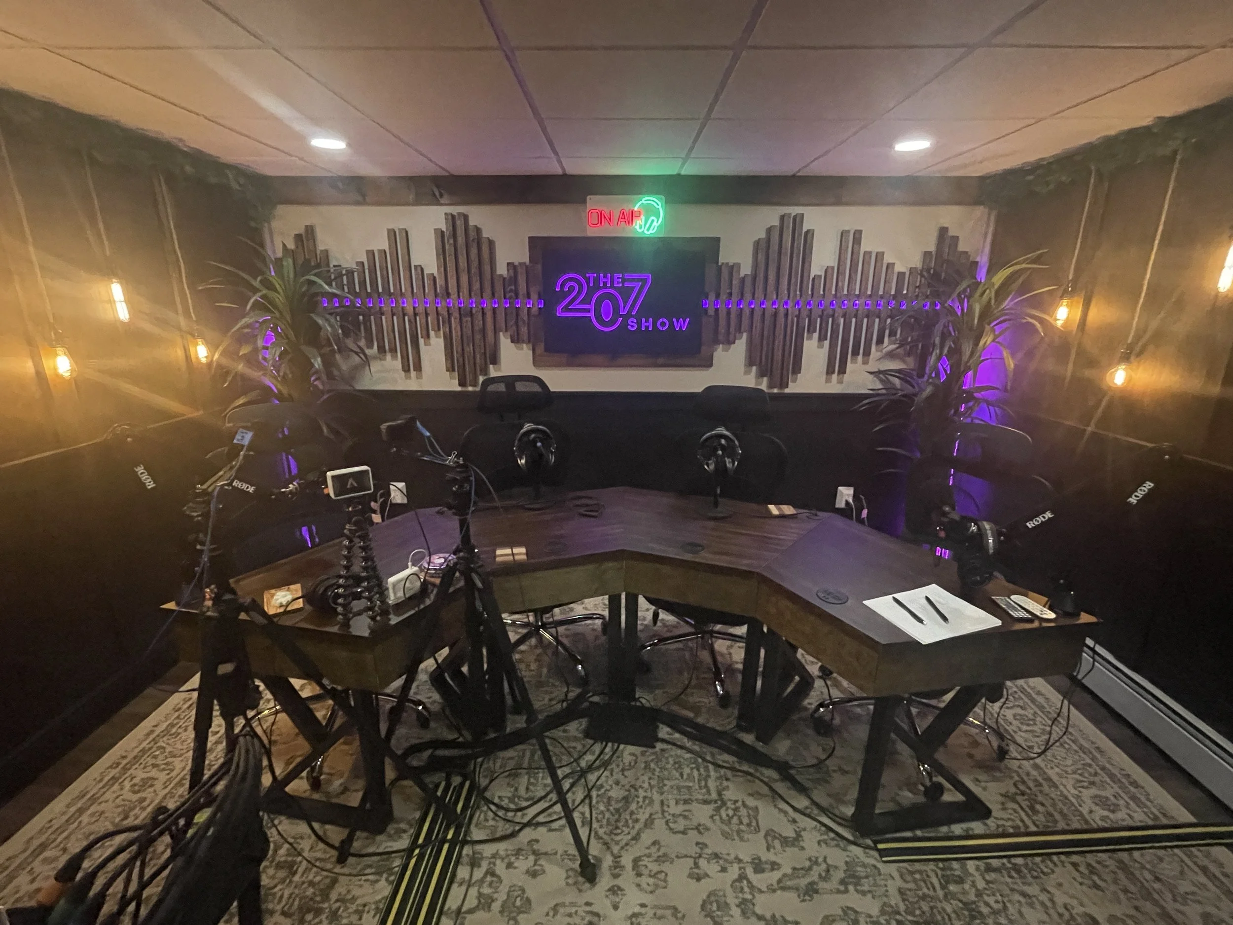 The 207 Show studio with warm lighting, microphones, and its illuminated purple logo