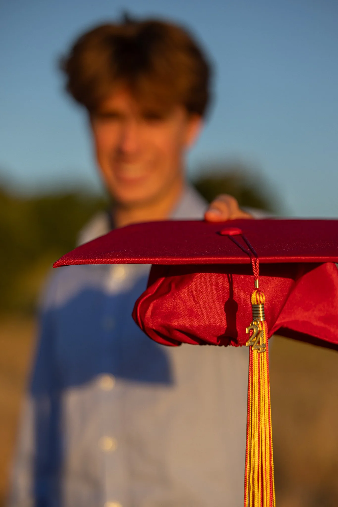 Person holding a red graduation cap with a 2024 tassel.