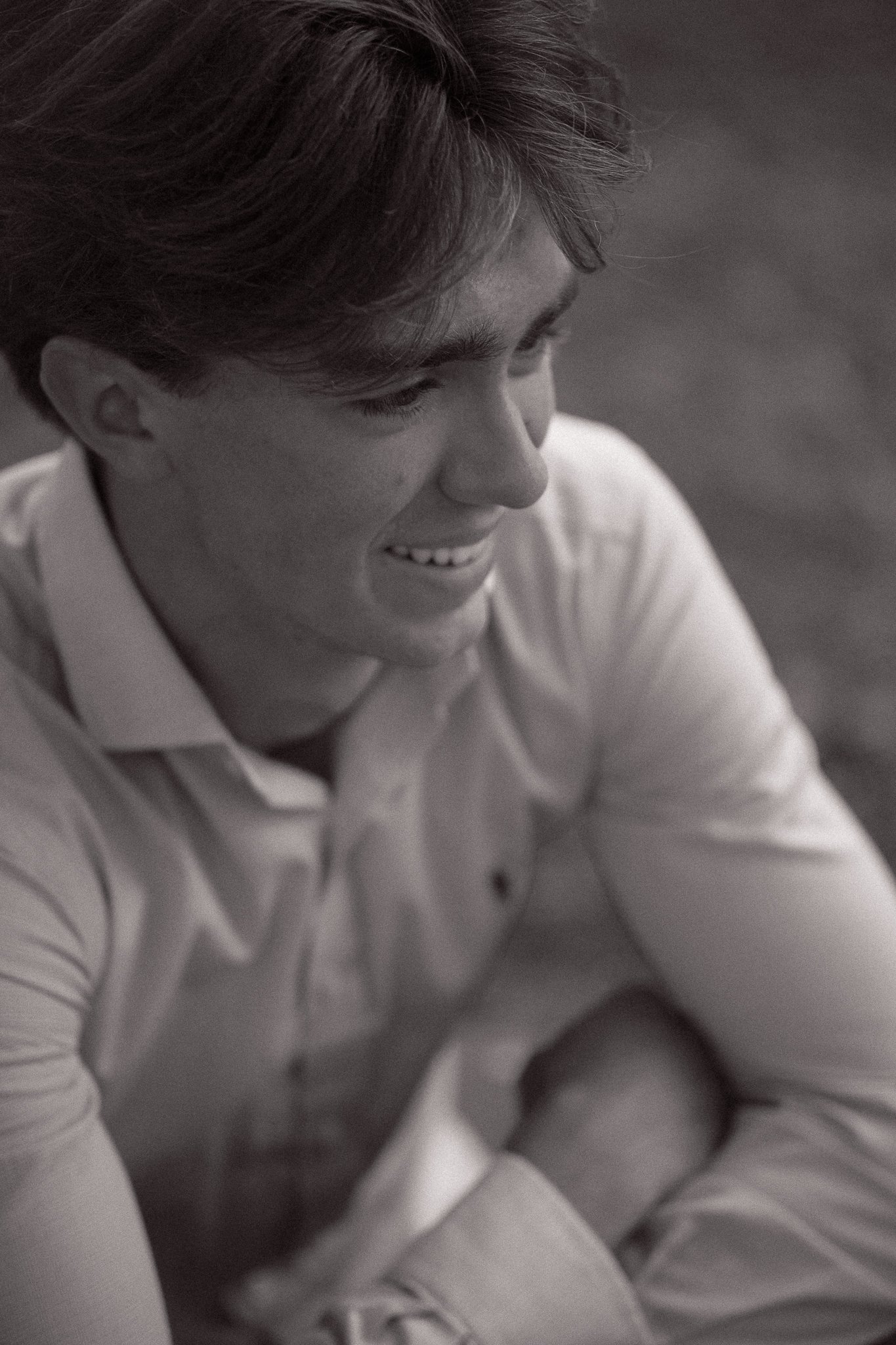Black and white photo of a young man smiling, wearing a collared shirt.