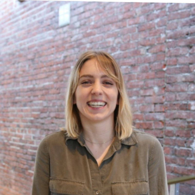 A picture of a blond woman smiling with brown shirt