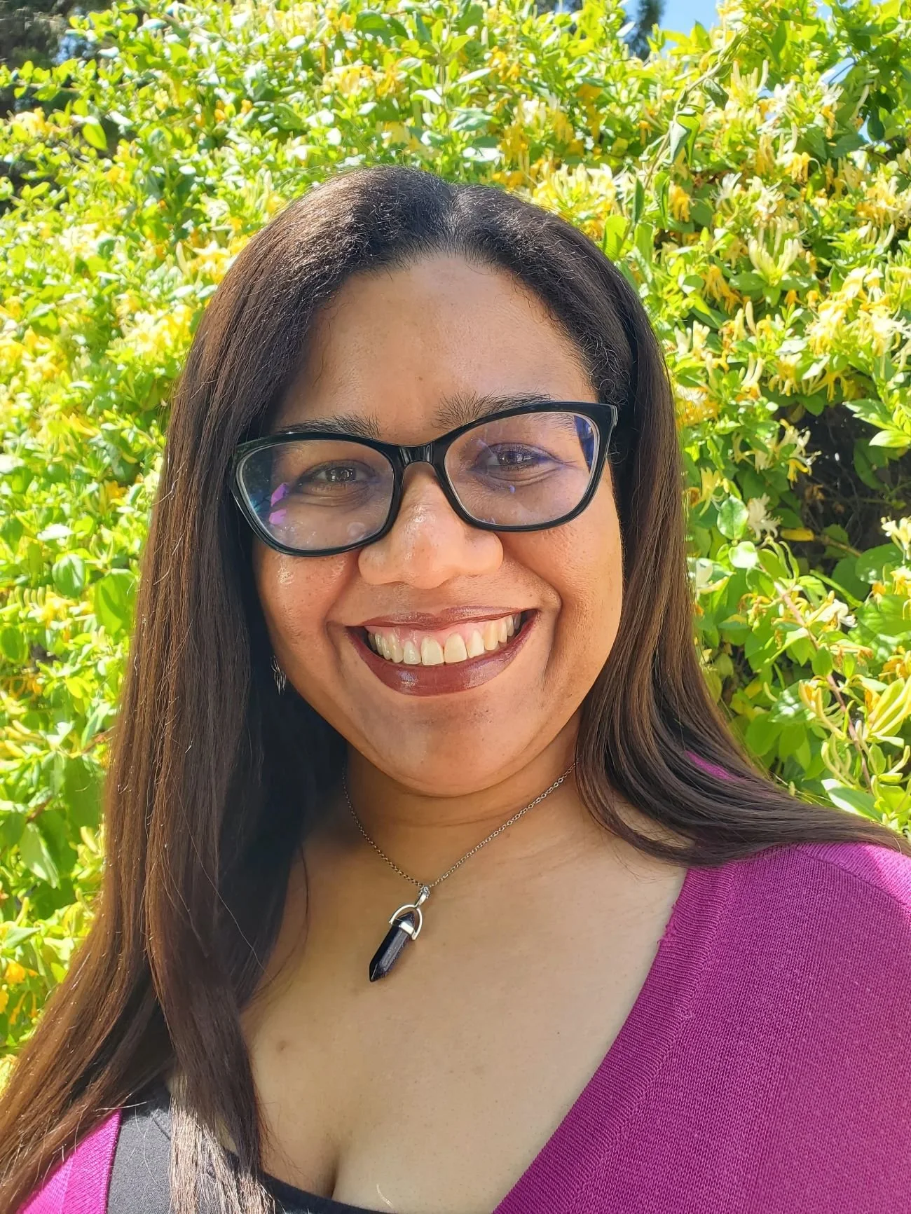 Aisha Subia smiling in front of honeysuckle bush