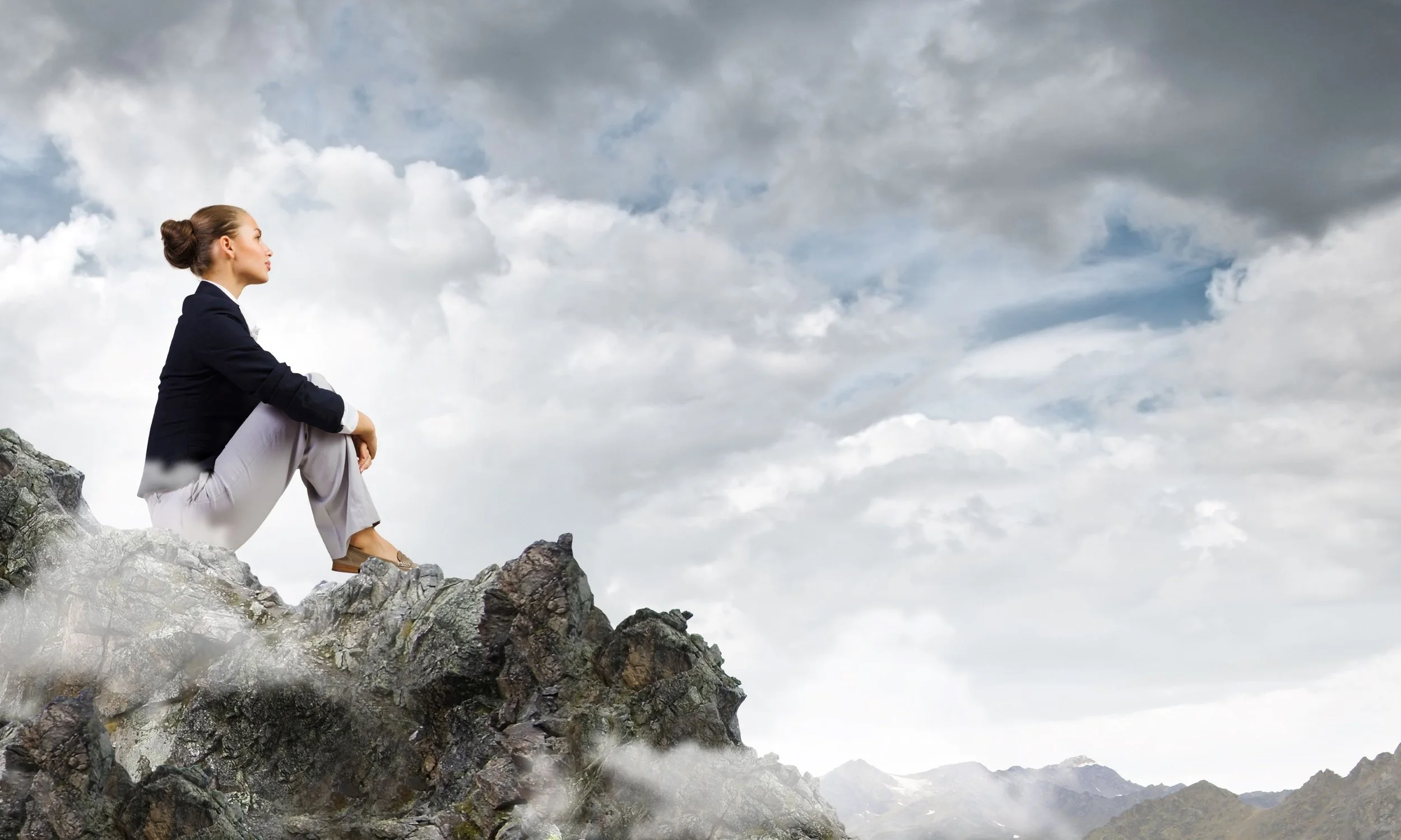 Business woman lives her vision of sitting on cloudy mountaintop