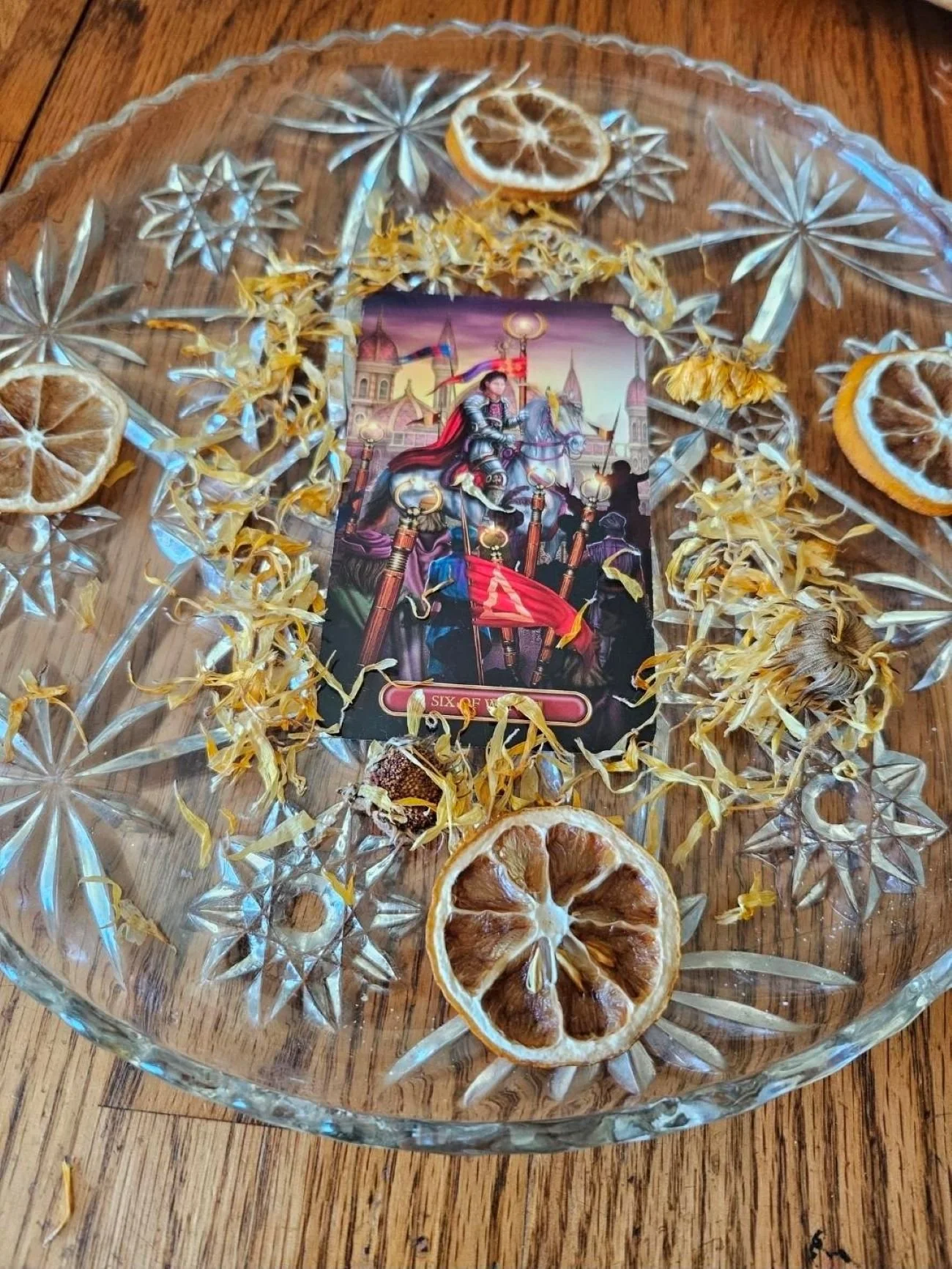 An altar with 6 of Wands card with lemon slices and calendula