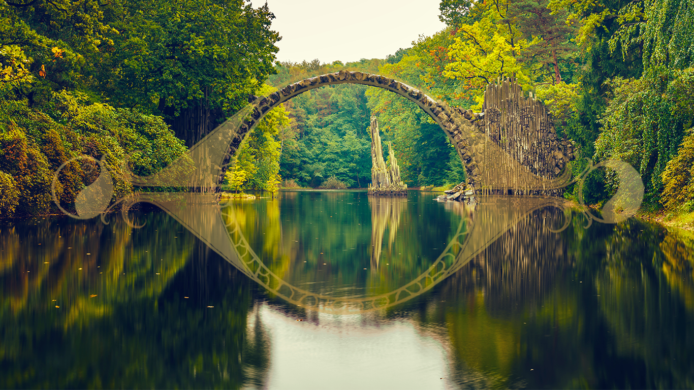 A stone bridge arches over reflection in the water to become a complete circle