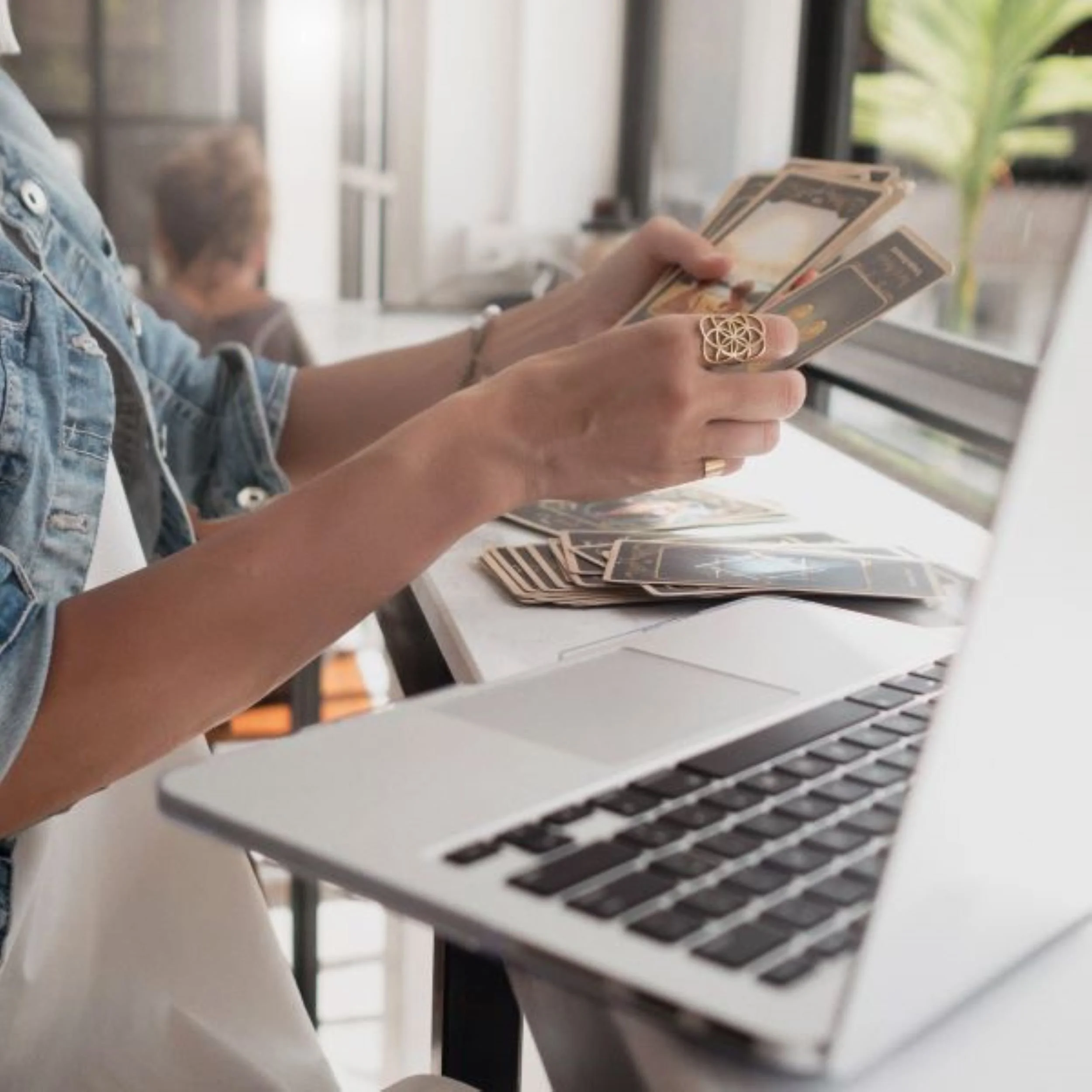 Woman reading tarot cards next to her laptop
