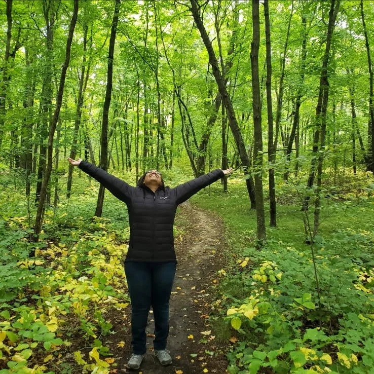 Aisha the Business Witch celebrates in a beautiful green forest
