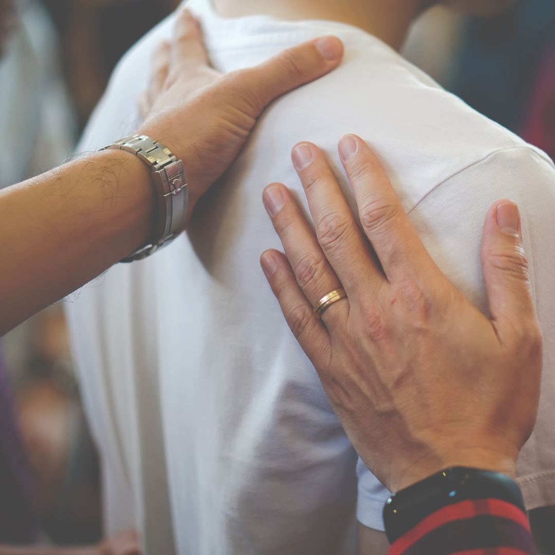 Hands placed on a person's shoulder and back during a handshake or comforting gesture.