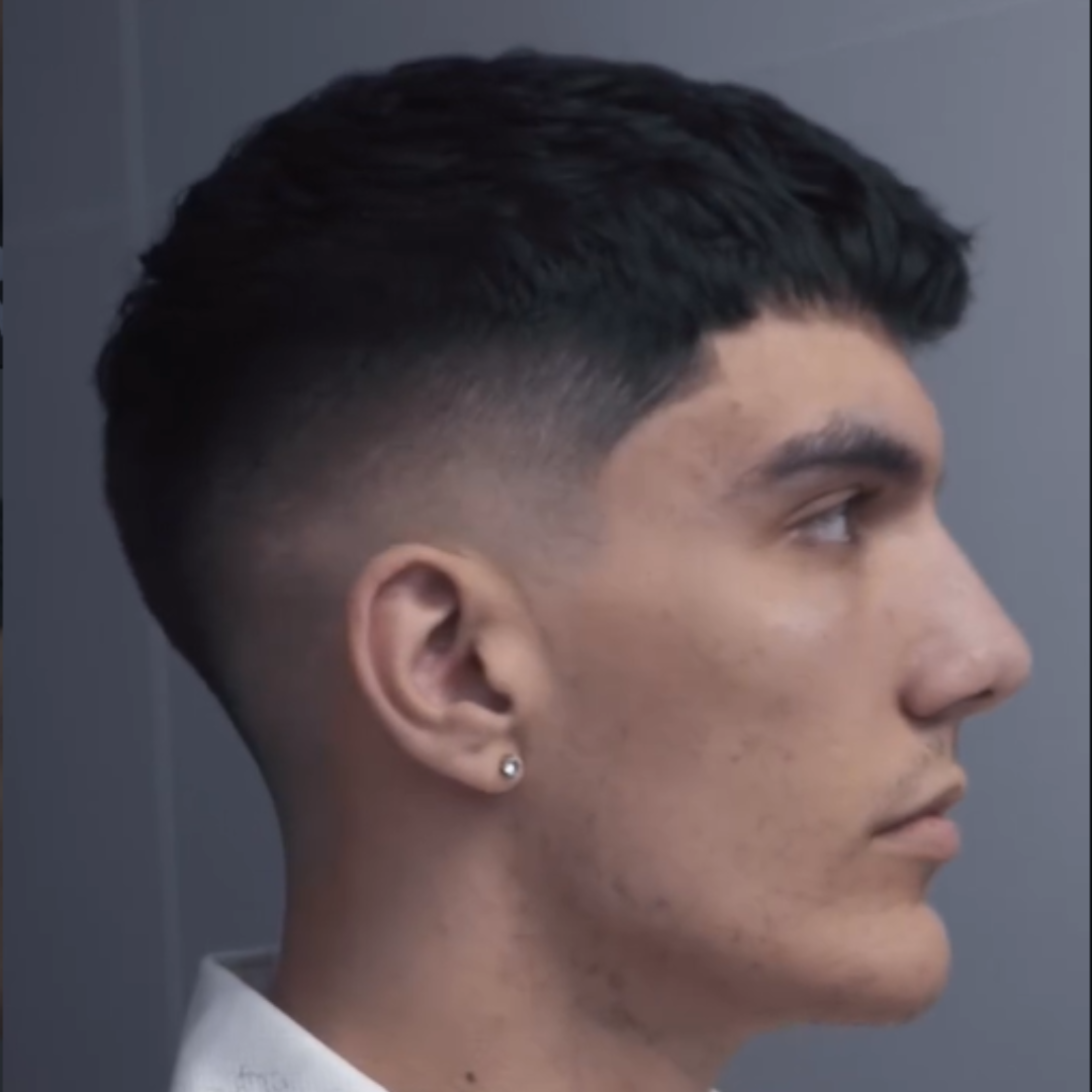 Side profile of a young man with dark, short, fades hairstyle and an earring.