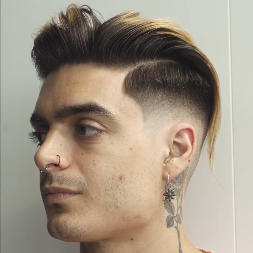 Side profile of a young man with styled, two-tone hair, facial piercings, and a tattoo on his neck.