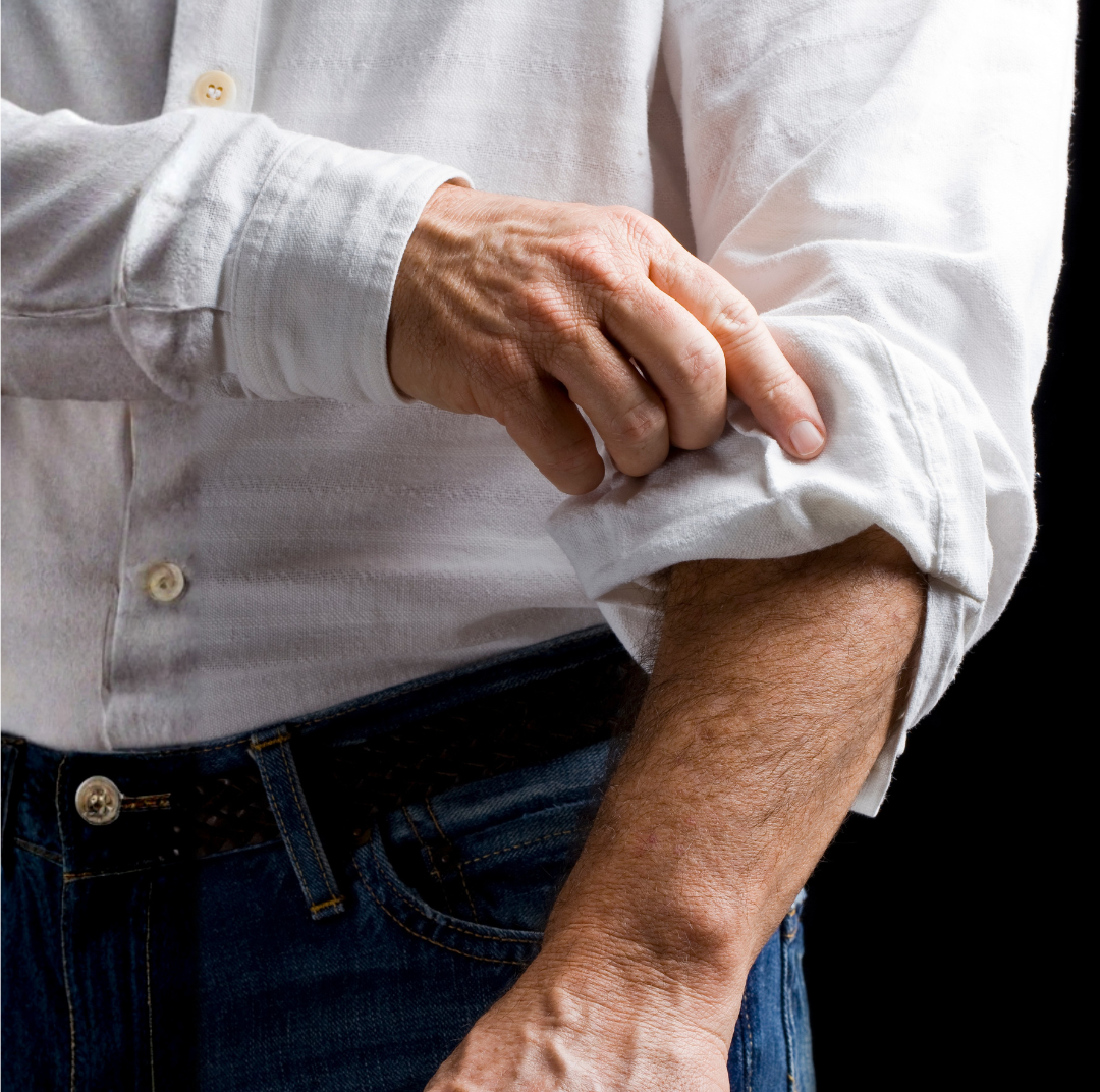 A person rolling up the sleeve of a white shirt.