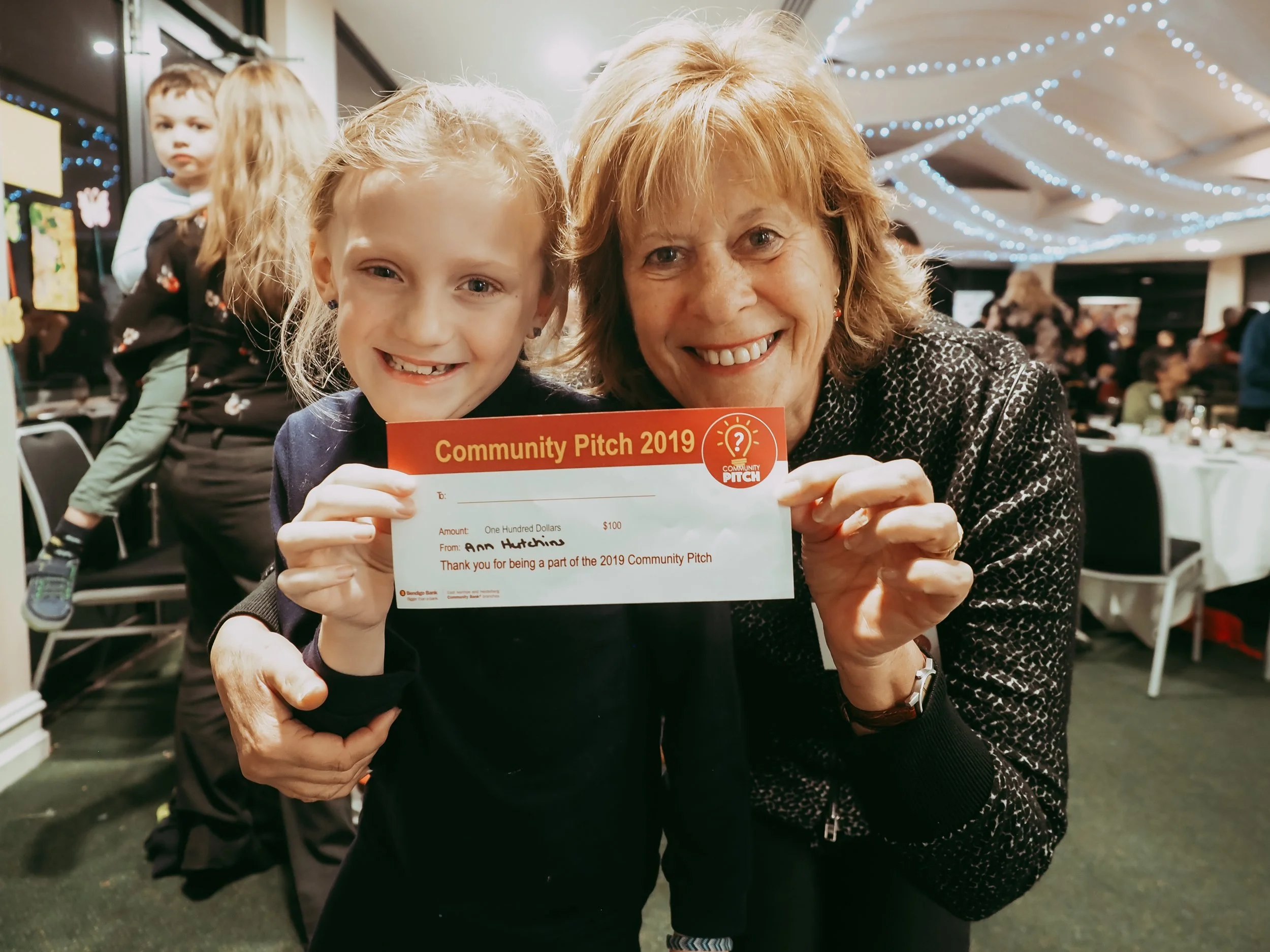 A woman and child smile as they hold up a donation to a charity.