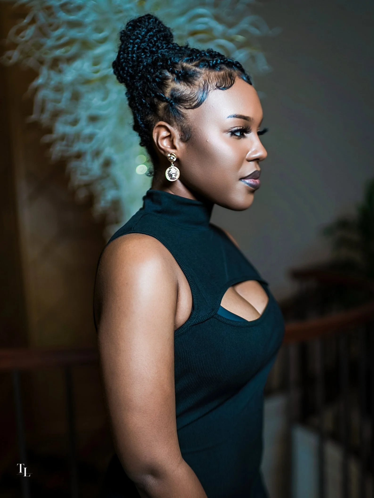 Side profile of an African American woman with styled twists and gold earrings, wearing a sleeveless dark teal top.