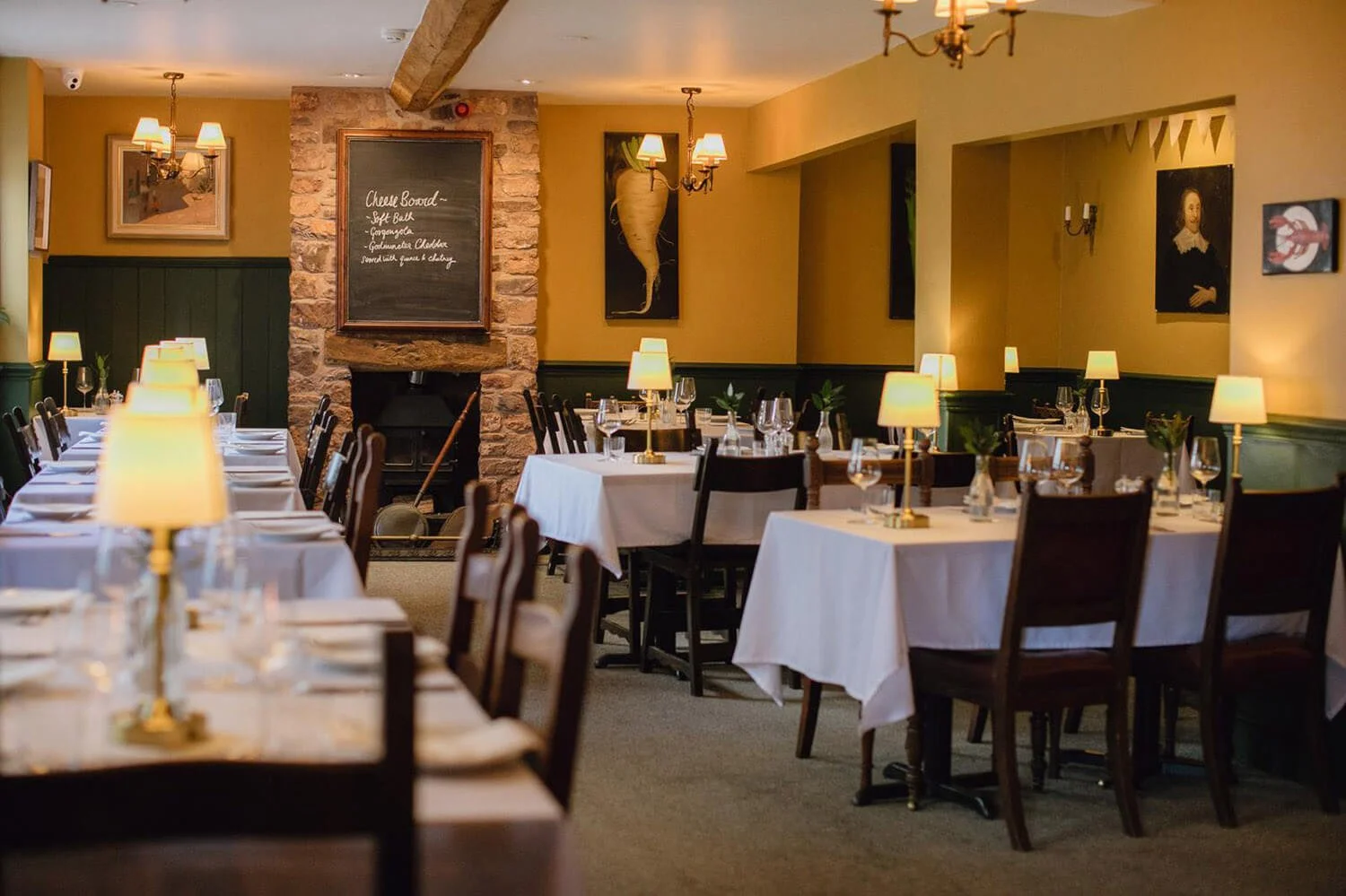 Interior of White Hart Wiveliscombe showing yellow walls and tables with lamps and table cloths on them