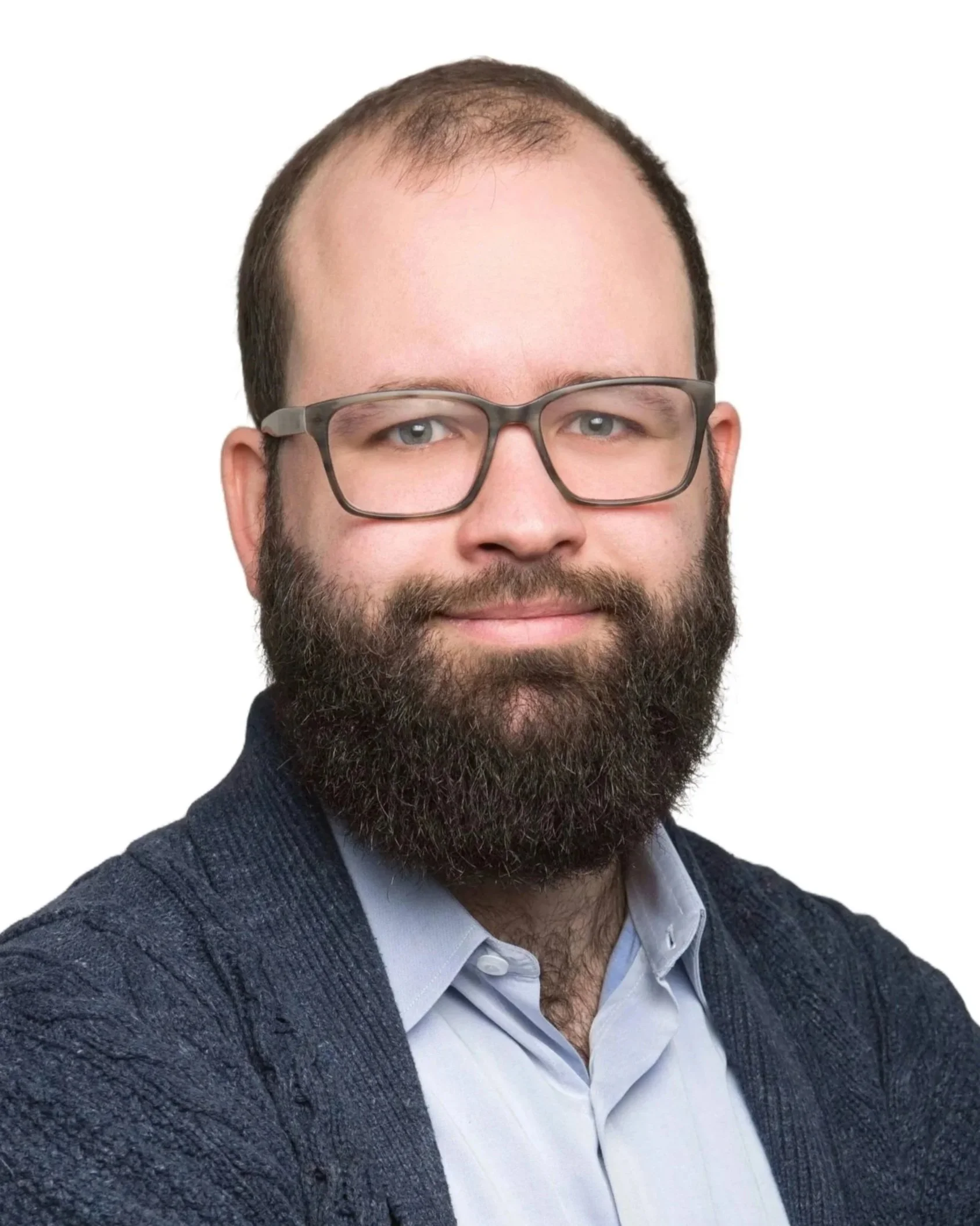 A man with glasses, a beard, and a short haircut, wearing a white button-up shirt and a dark sweater, smiling against a white background.