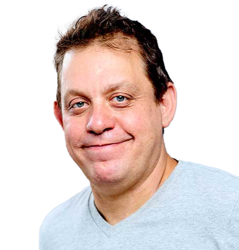 A man with light skin, short brown hair, and blue eyes, smiling and wearing a light gray shirt.