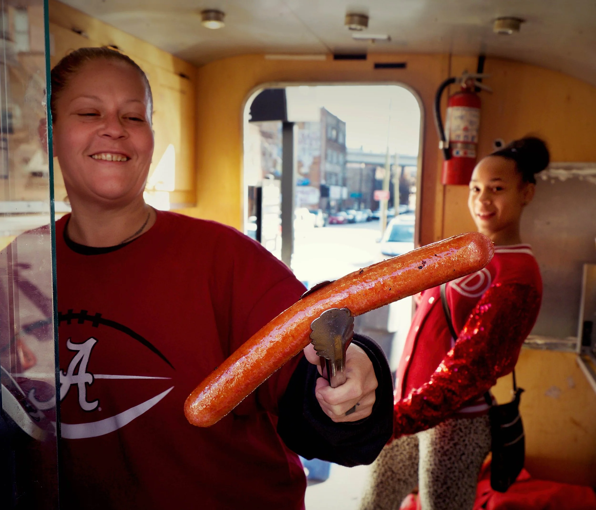 Woman serving a long sausage from a food truck in Nashville with warm afternoon light