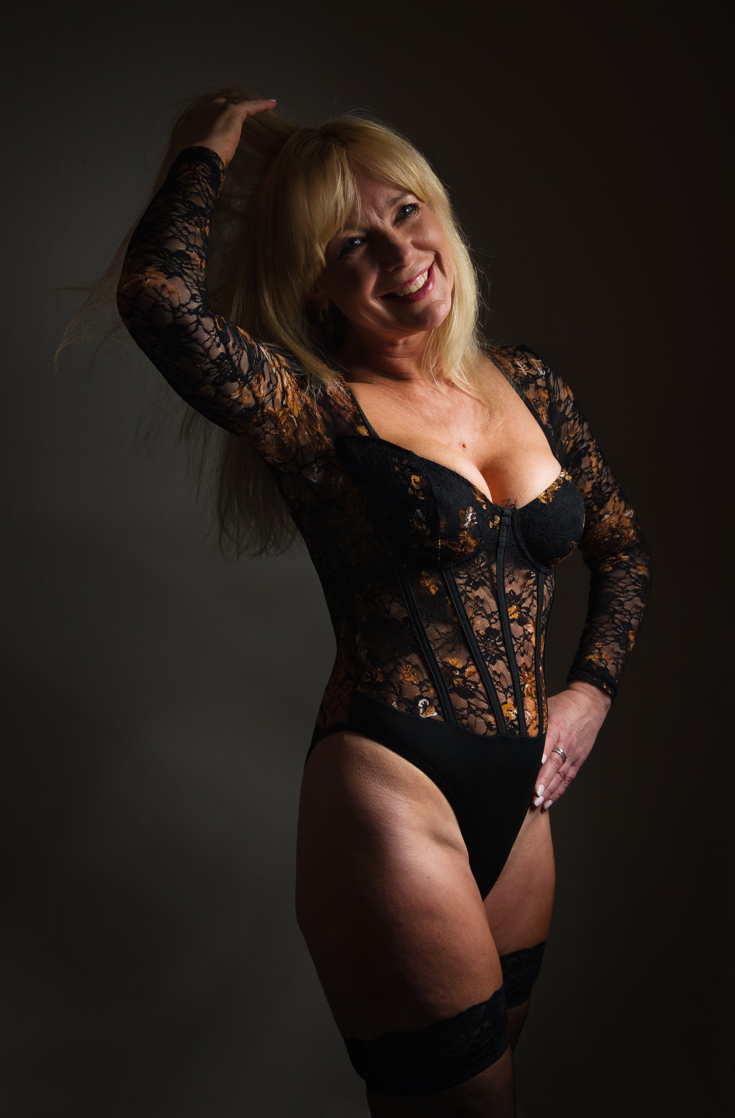 Boudoir portrait of a smiling woman in black lace bodysuit