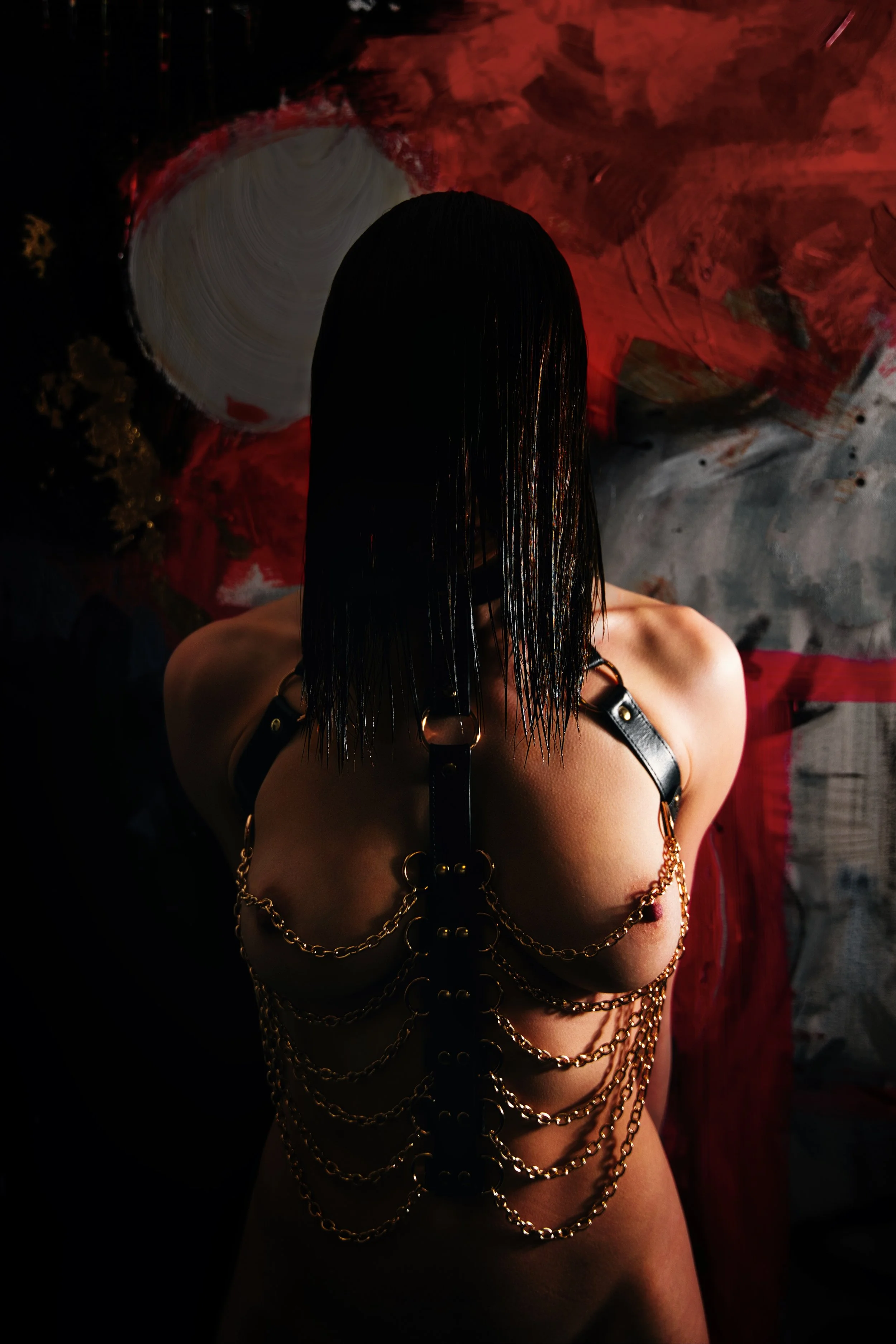 Artistic nude portrait in front of a painting with dramatic red light