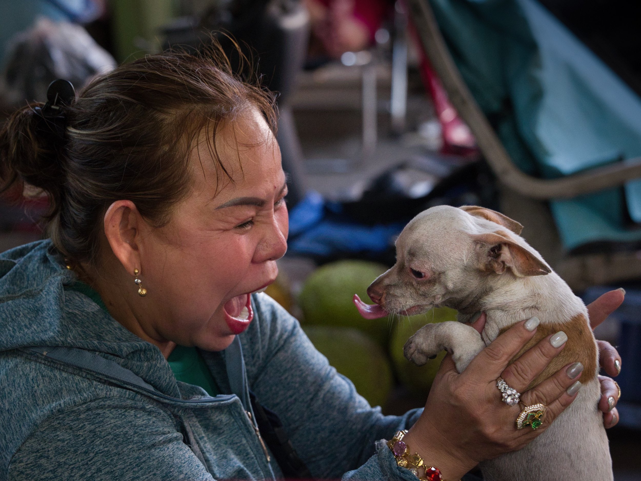 Woman holding a small dog in a candid moment on a street in Ho Chi Minh City