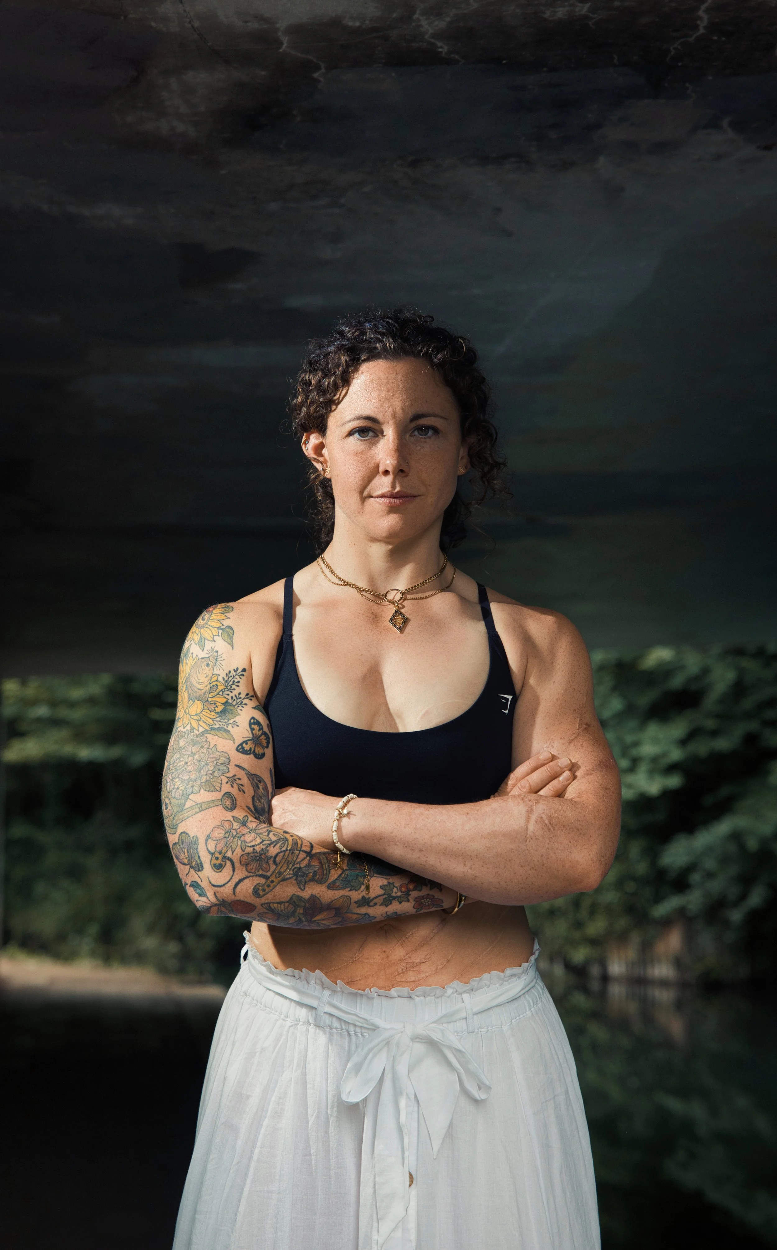 Portrait of a tattooed female athlete standing beneath a canal bridge in Gloucestershire.