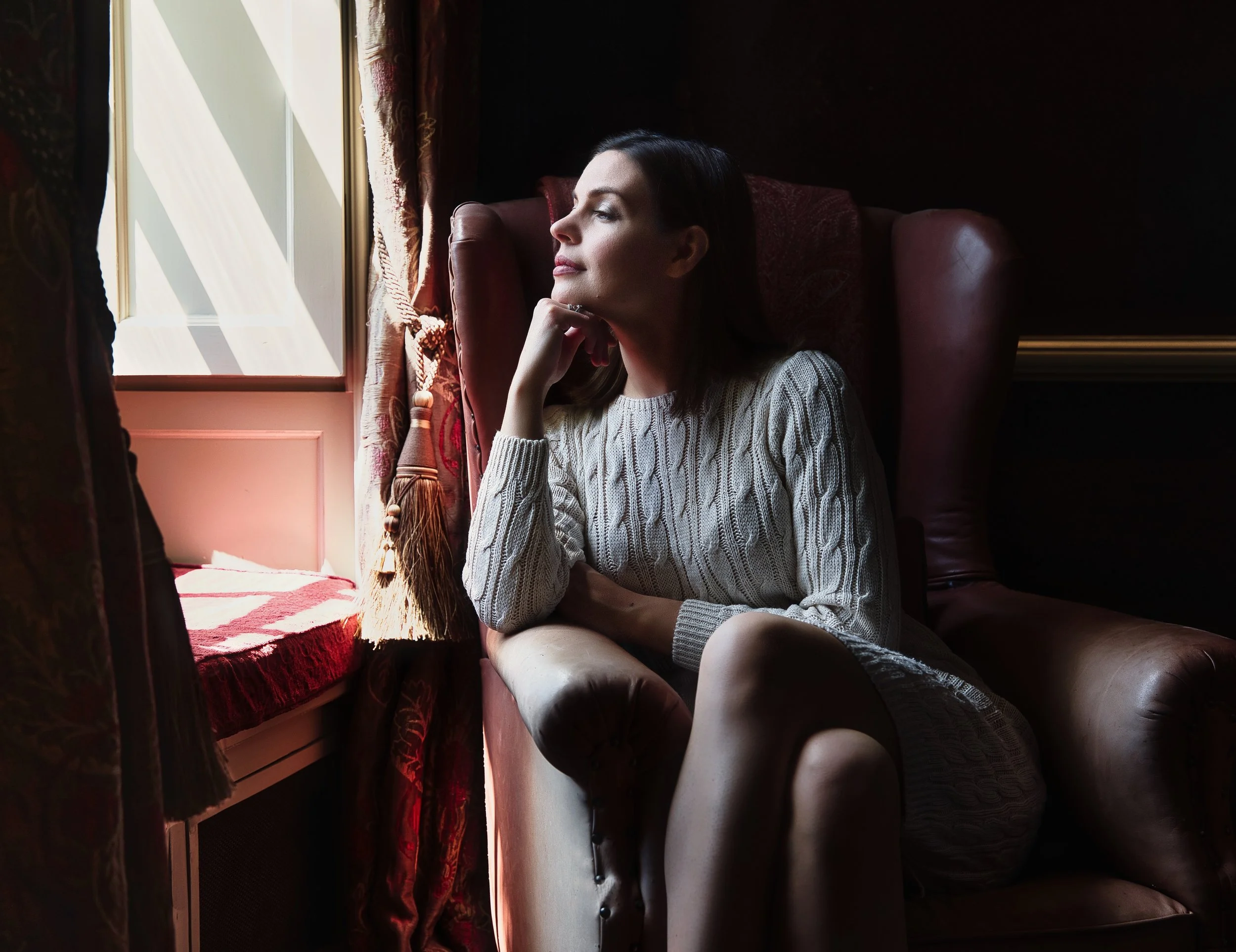 Portrait of a woman sitting beside a window in soft natural light