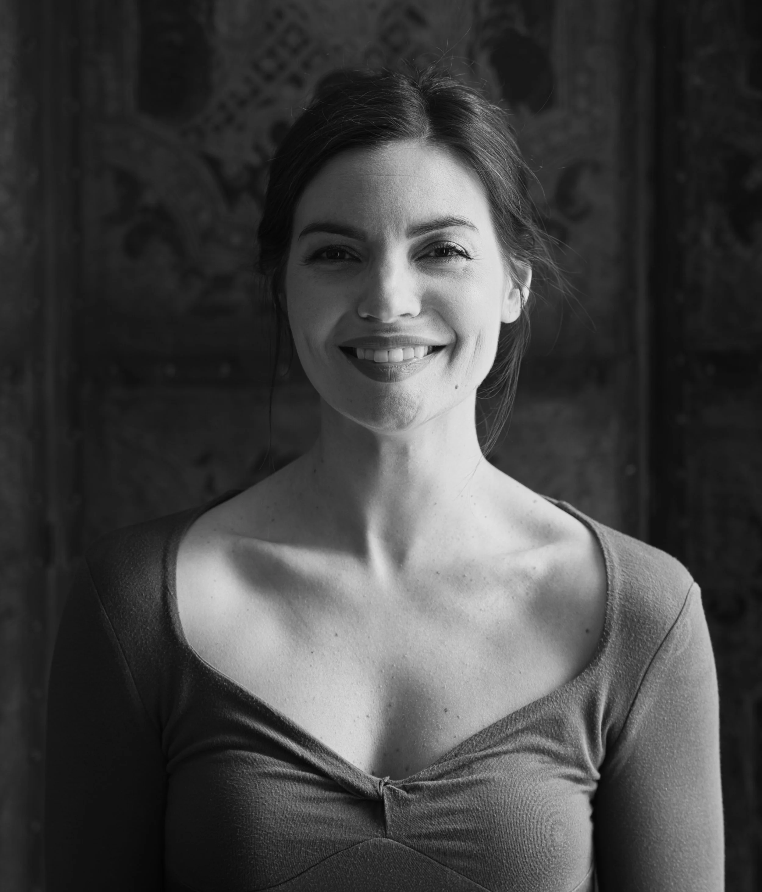 Black and white portrait of a smiling woman in soft window light